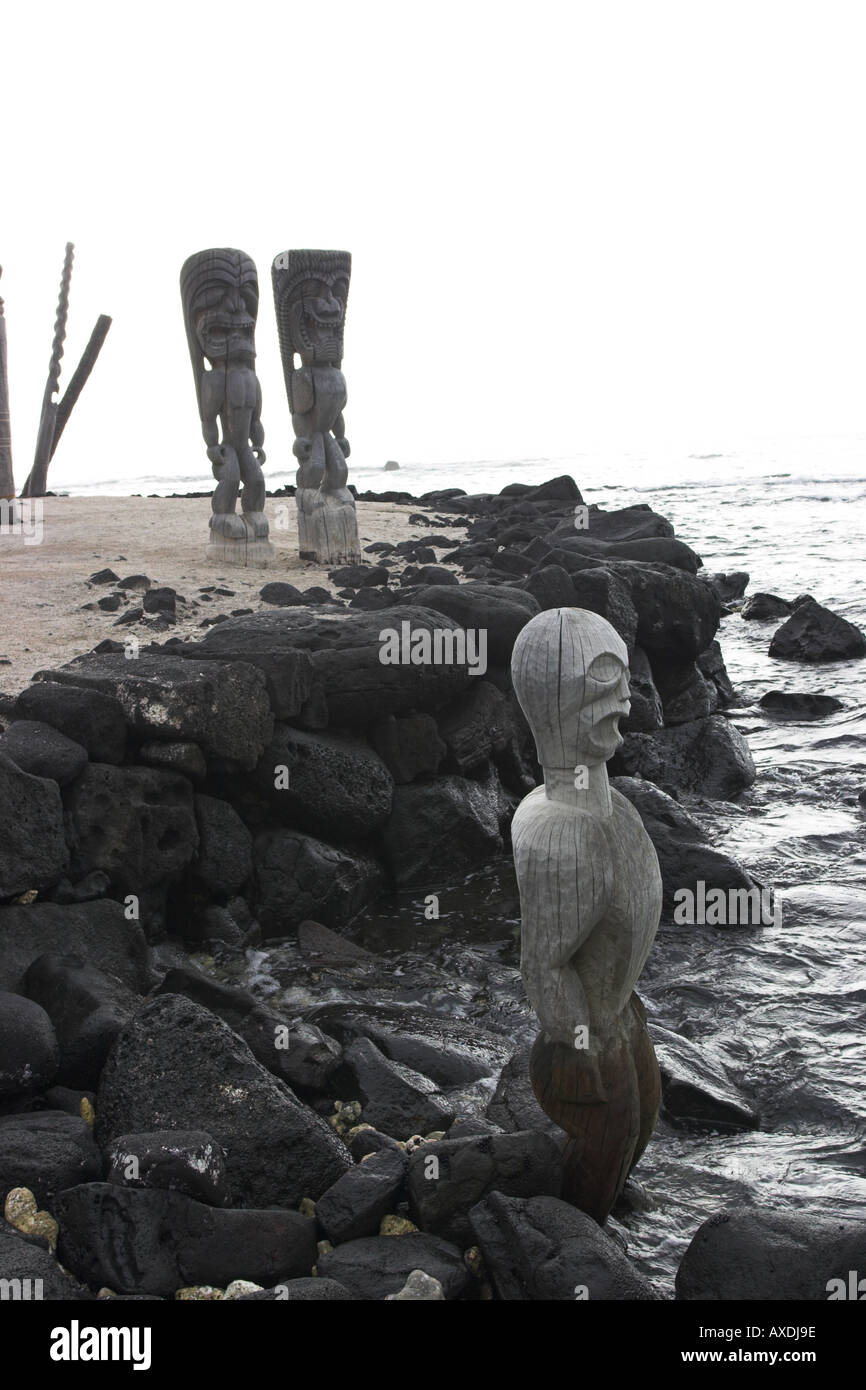 Guardián estatuas tiki en el borde del océano Lugar de refugio Pu uhonua o Honaunau Hawaii Big Island EE.UU. Foto de stock