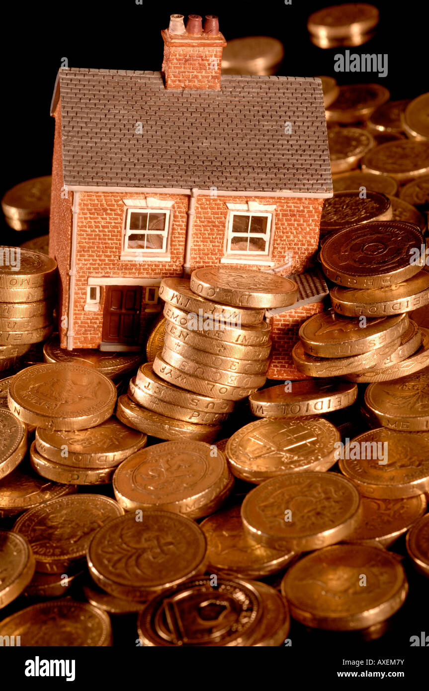 Una casa hundido en deuda con British Pound monedas Foto de stock