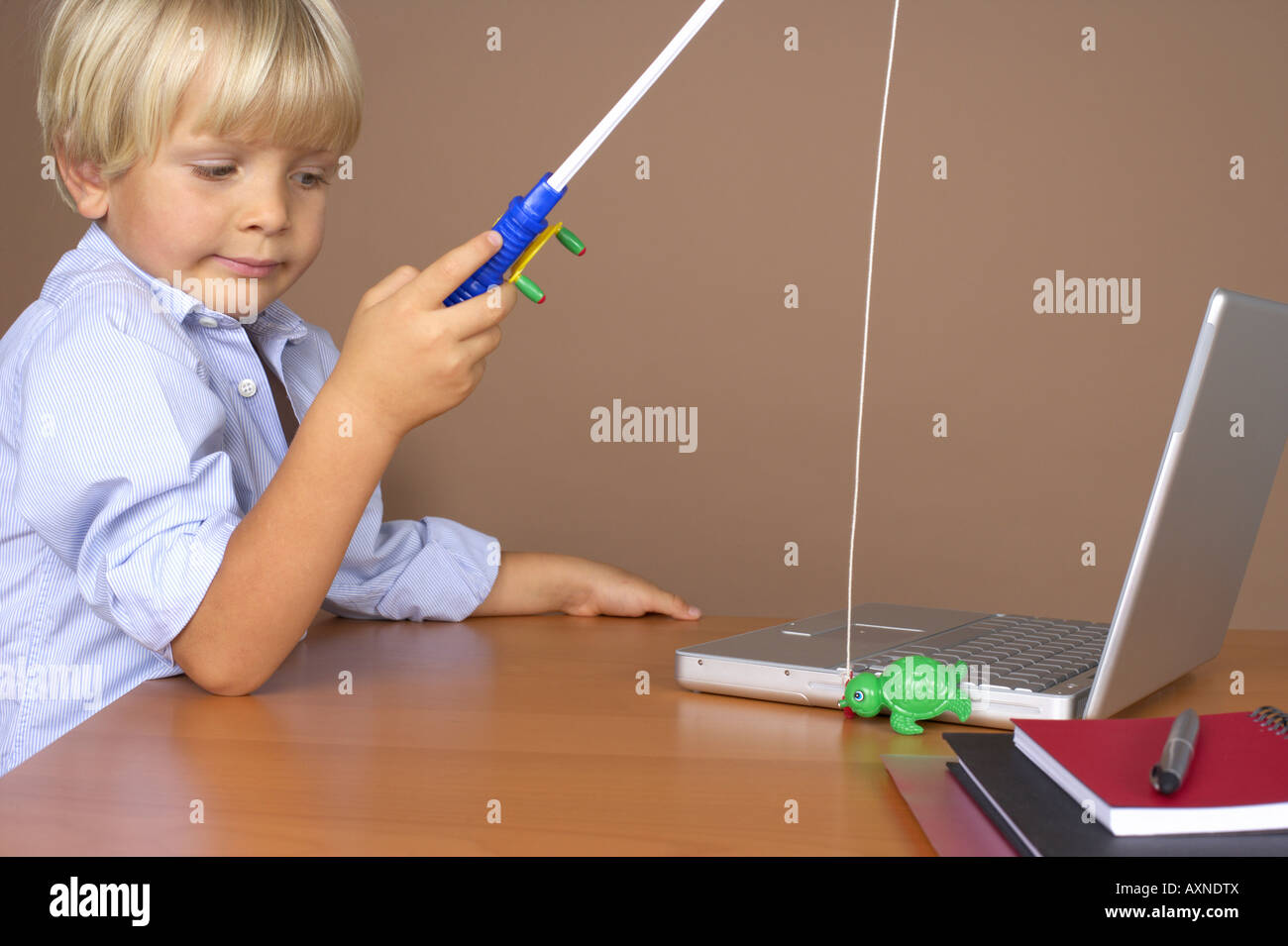 Niño (4-5 años) jugando con un juguete caña de pescar junto a un ordenador  portátil Fotografía de stock - Alamy