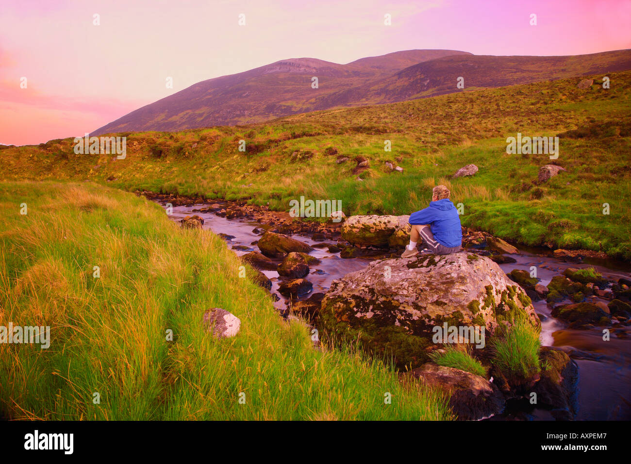 El condado de Donegal, Irlanda, persona sentada sobre una roca Foto de stock