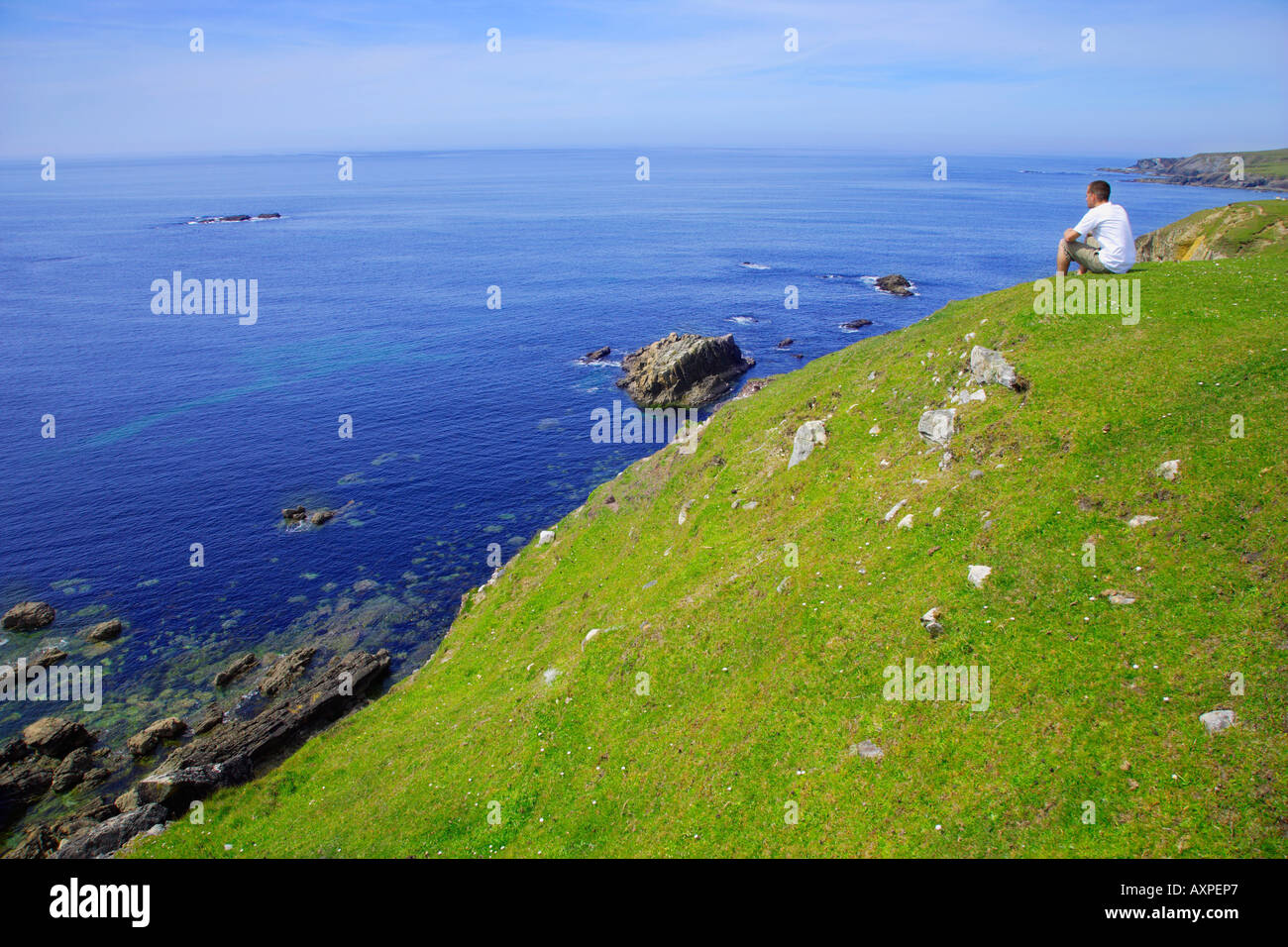 El condado de Donegal, Irlanda, hombre sentado cerca de la costa Foto de stock
