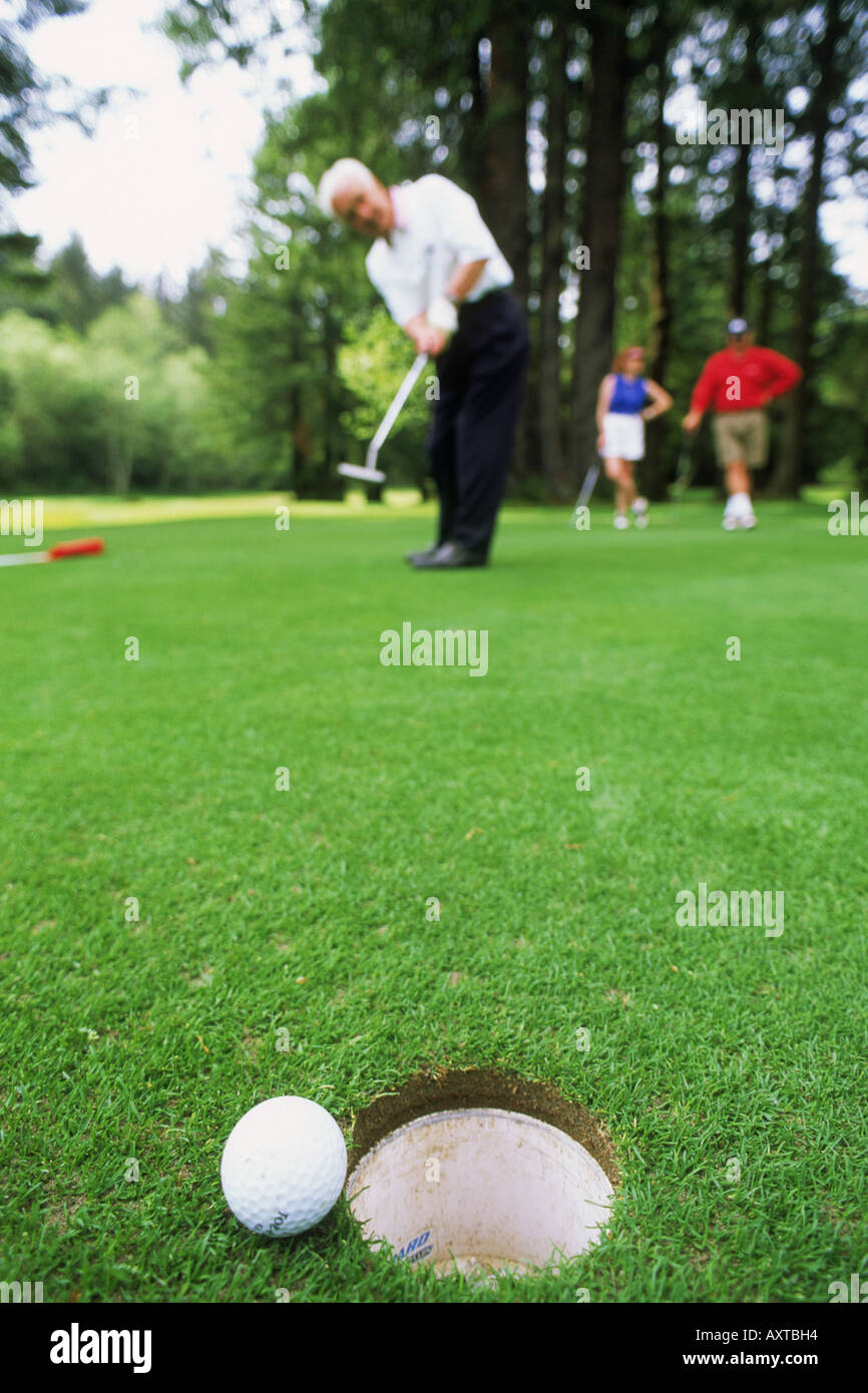 Pelota de golf colgando del borde del agujero después de mucho el putt. Foto de stock