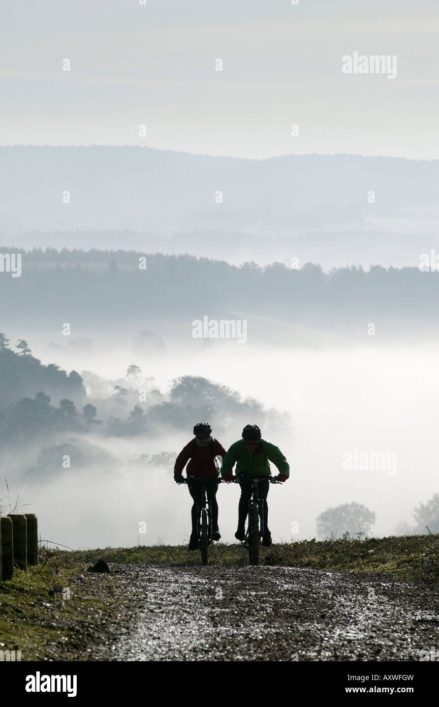 Dos bicicletas de montaña a subir una pendiente, Newlands Corner, cerca de Guildford, Surrey Hills, Surrey, Inglaterra, Reino Unido. Foto de stock