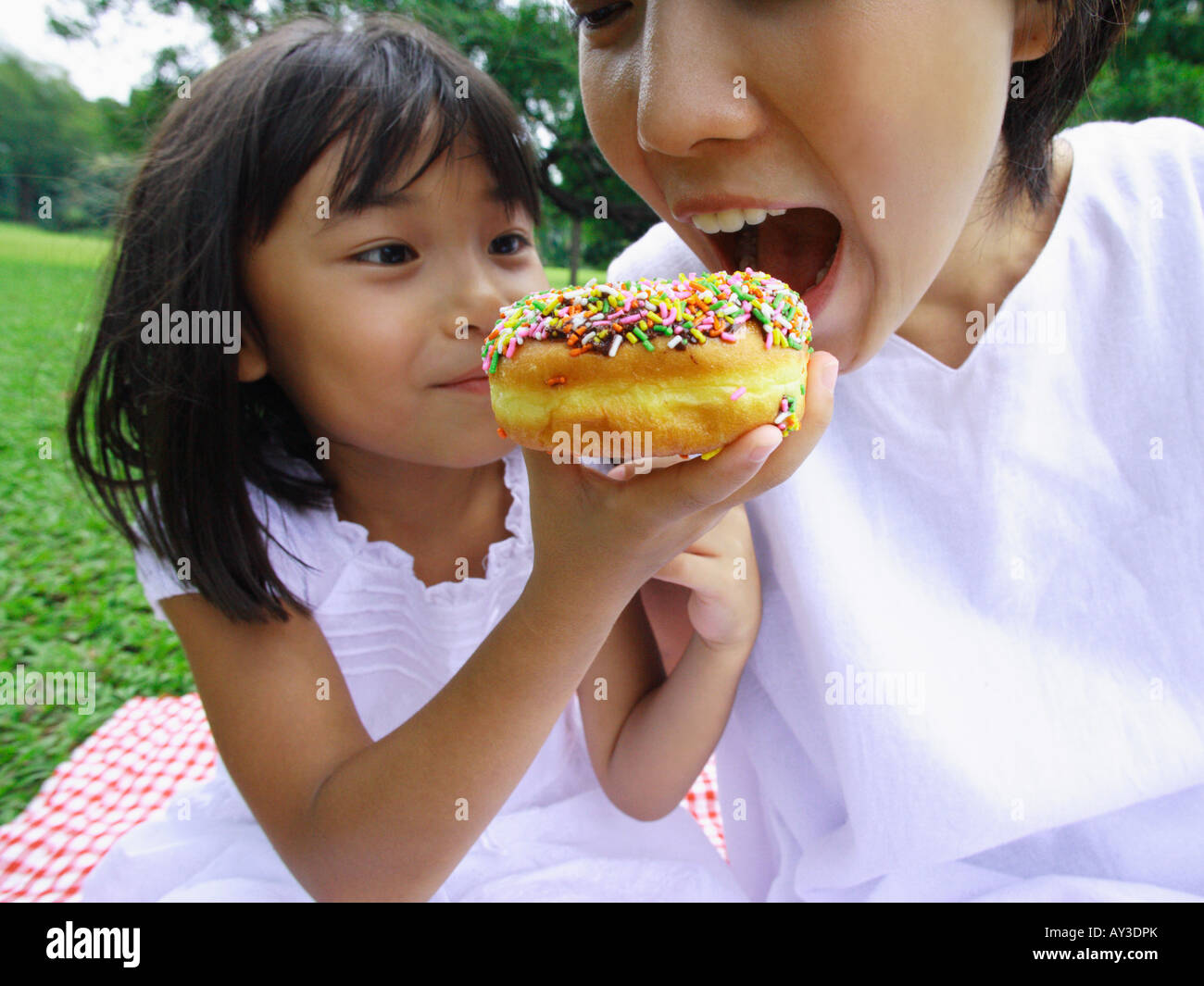 Close-up de una chica alimentando un donut a su madre Foto de stock