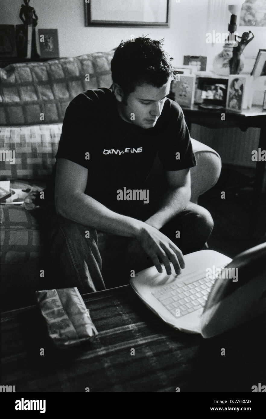 Retroiluminación en blanco y negro de un hombre joven con un Apple iBook en un salón Foto de stock
