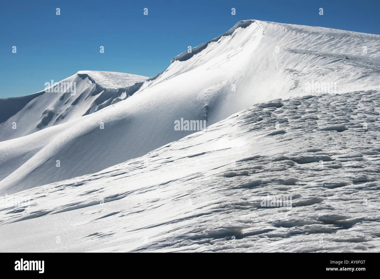 Montañas invernales ridge con saliente de nieve y snowboard caps las pistas de fondo de cielo azul. Foto de stock