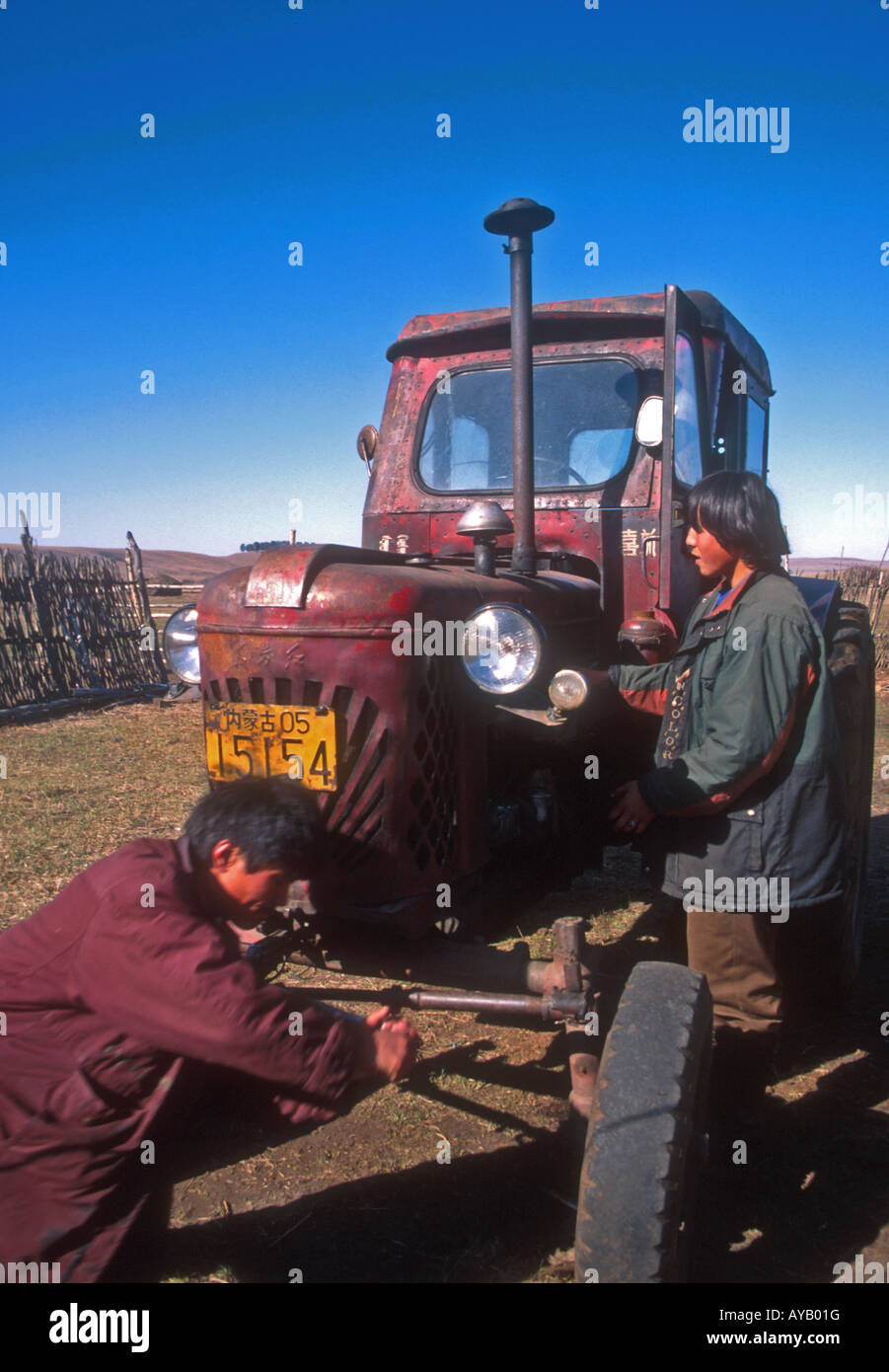 Granja de Mongolia chicos reparación era soviética el tractor en la granja en Hulun Buir pastizales del noreste de Mongolia Interior. Foto de stock
