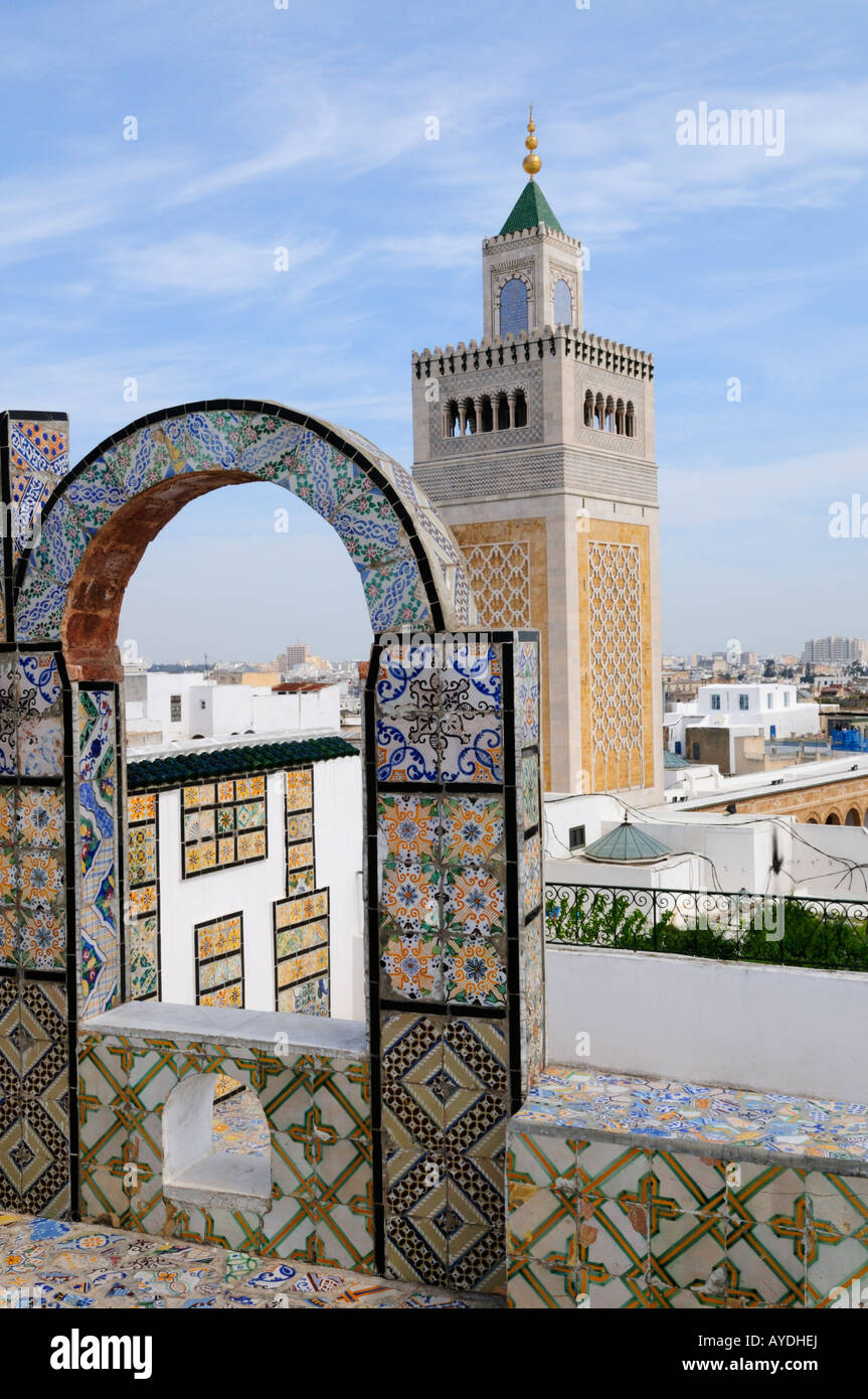 Minarete de la Gran Mezquita y un arco de mosaico en una terraza en la azotea, Túnez Foto de stock