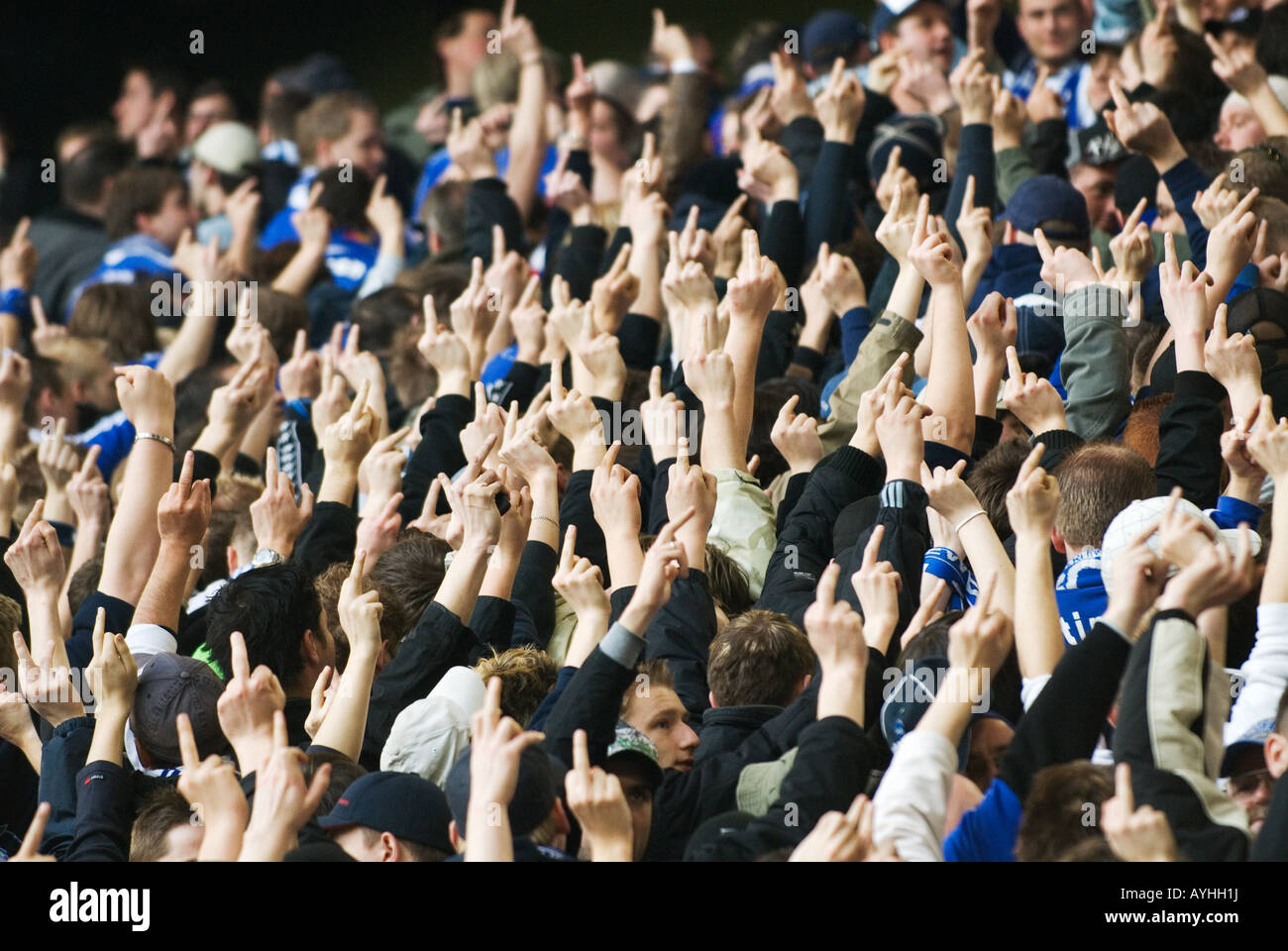 Los aficionados al fútbol de Schalke 04 muestran sus dedos outstreched al equipo contrario Foto de stock