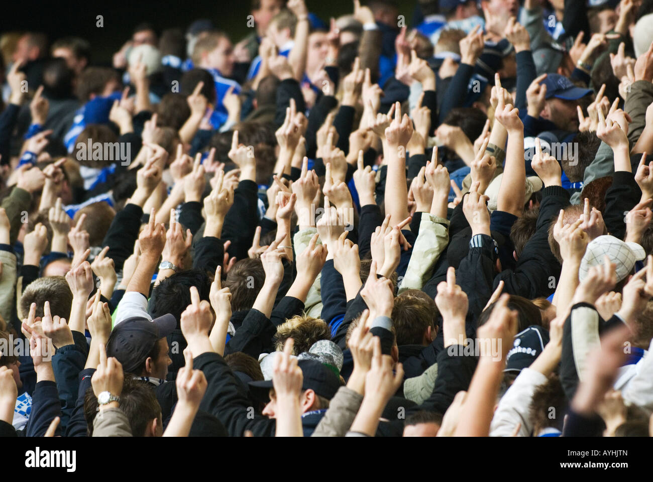 Los aficionados al fútbol de Schalke 04 muestran sus dedos outstreched al equipo contrario Foto de stock