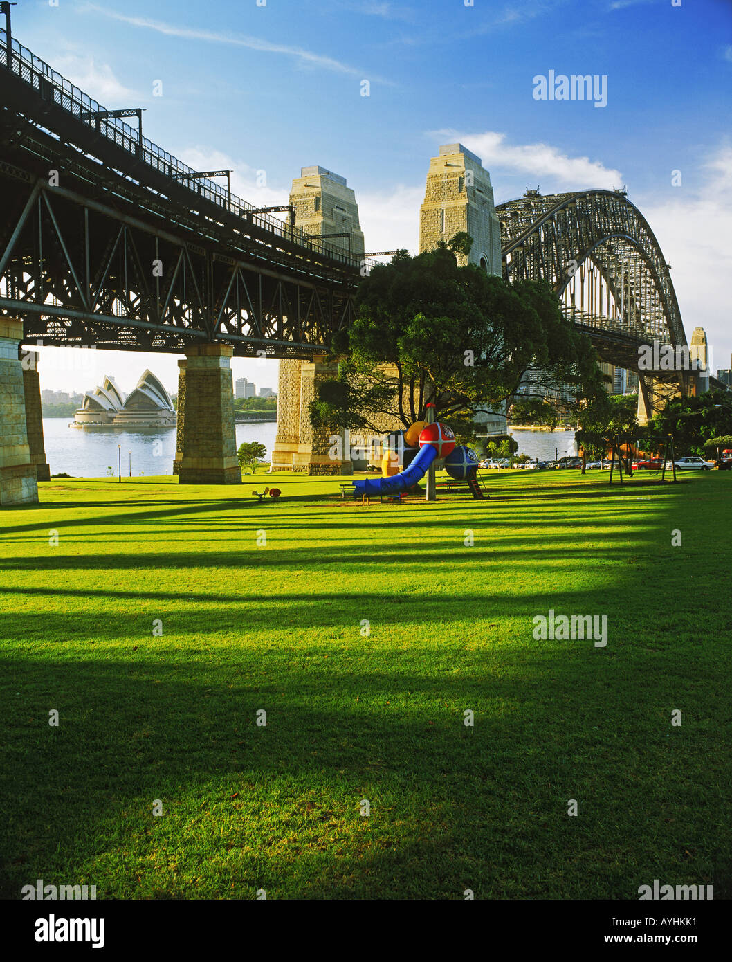 La luz de la mañana en el parque de hierba bajo el Harbour Bridge en Sydney Norte frente a la Casa de la Ópera Foto de stock