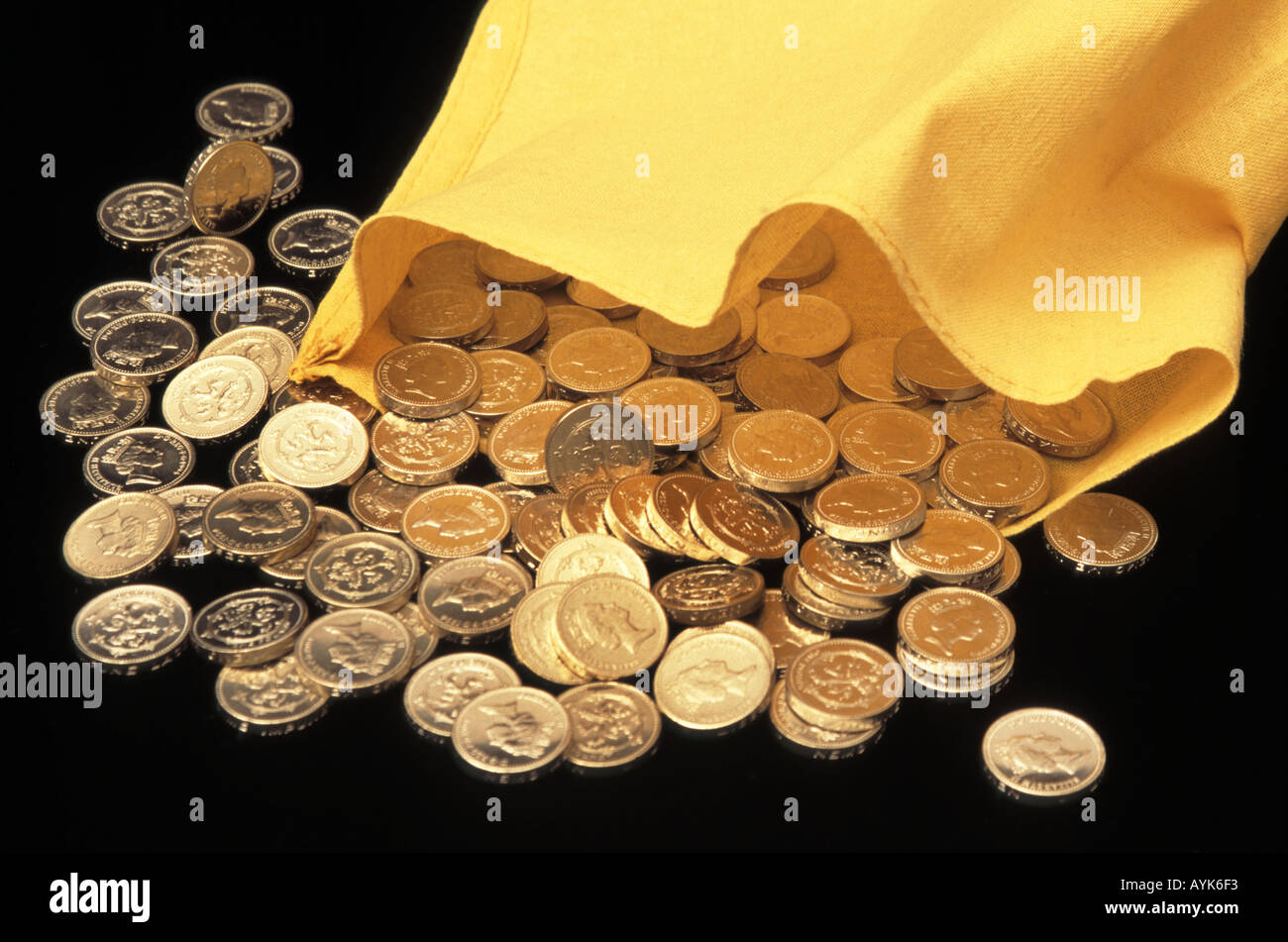 Primer plano de la pila de moneda británica en una libra de monedas de efectivo libra esterlina derramando fuera de libras de cambio suelto de la bolsa de dinero amarilla del banco Foto de stock