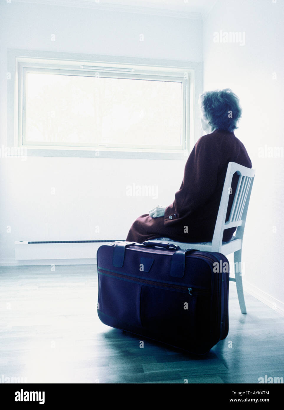 Anciana sentado en una habitación vacía con maleta Fotografía de stock -  Alamy