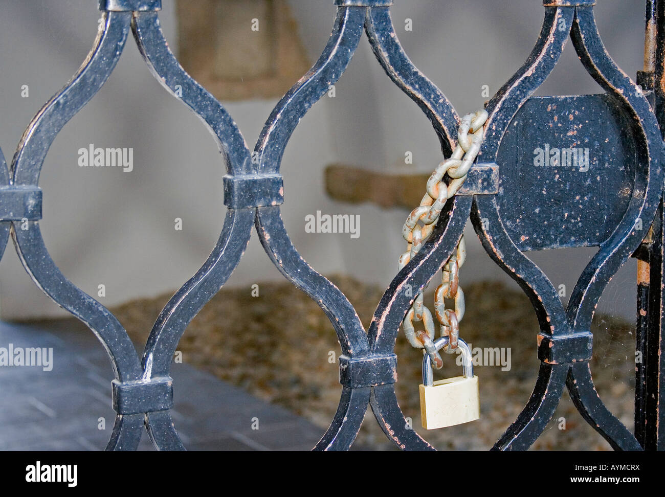 Puerta de barrotes de hierro oxidado con cadena y candado. Foto de stock