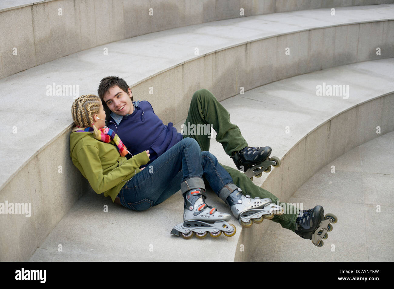 Pareja joven llevando patines en línea sentado en una escalera Fotografía  de stock - Alamy