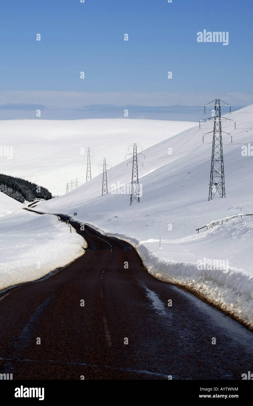 La A939, Carretera Lecht ejecutando desde Cockbridge en Tomintoul, Escocia, con nieve en las colinas de los alrededores en sol de invierno Foto de stock