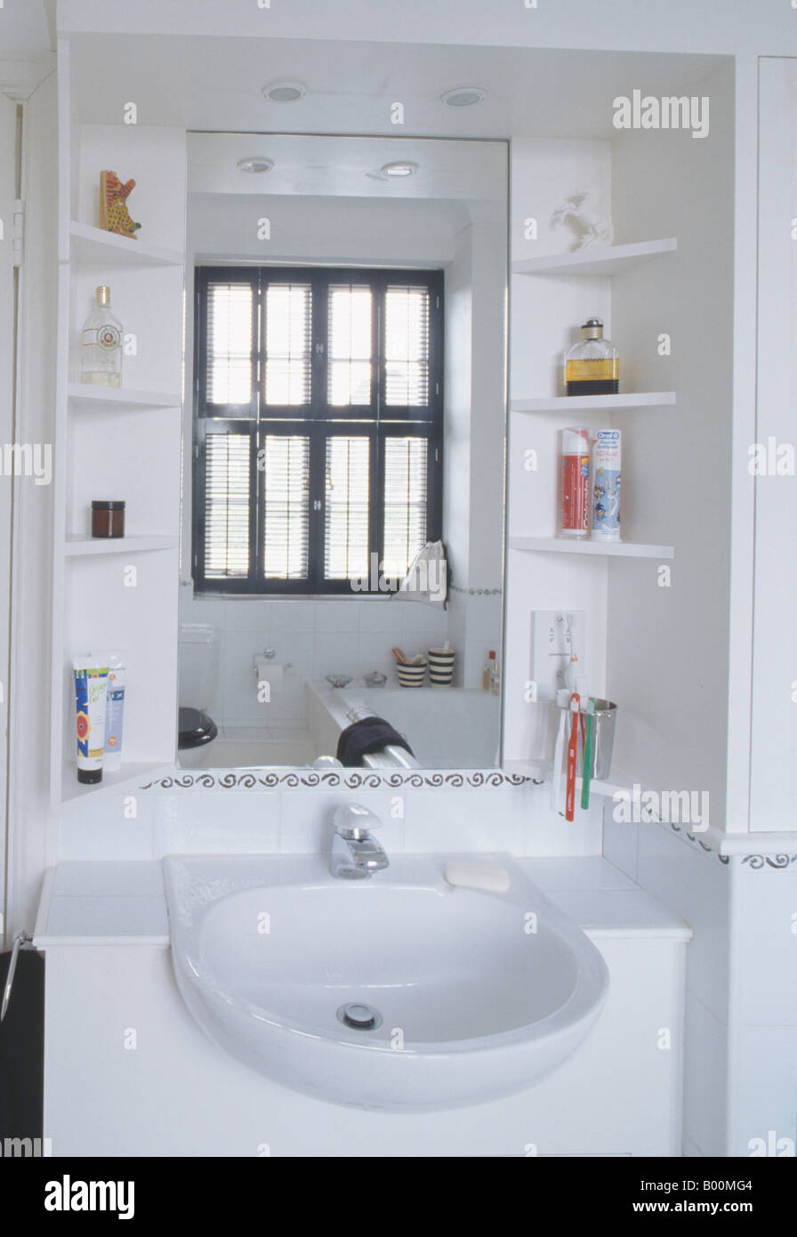 Cerca de estantes a cada lado del espejo sobre la cuenca del blanco en un  cuarto de baño moderno Fotografía de stock - Alamy