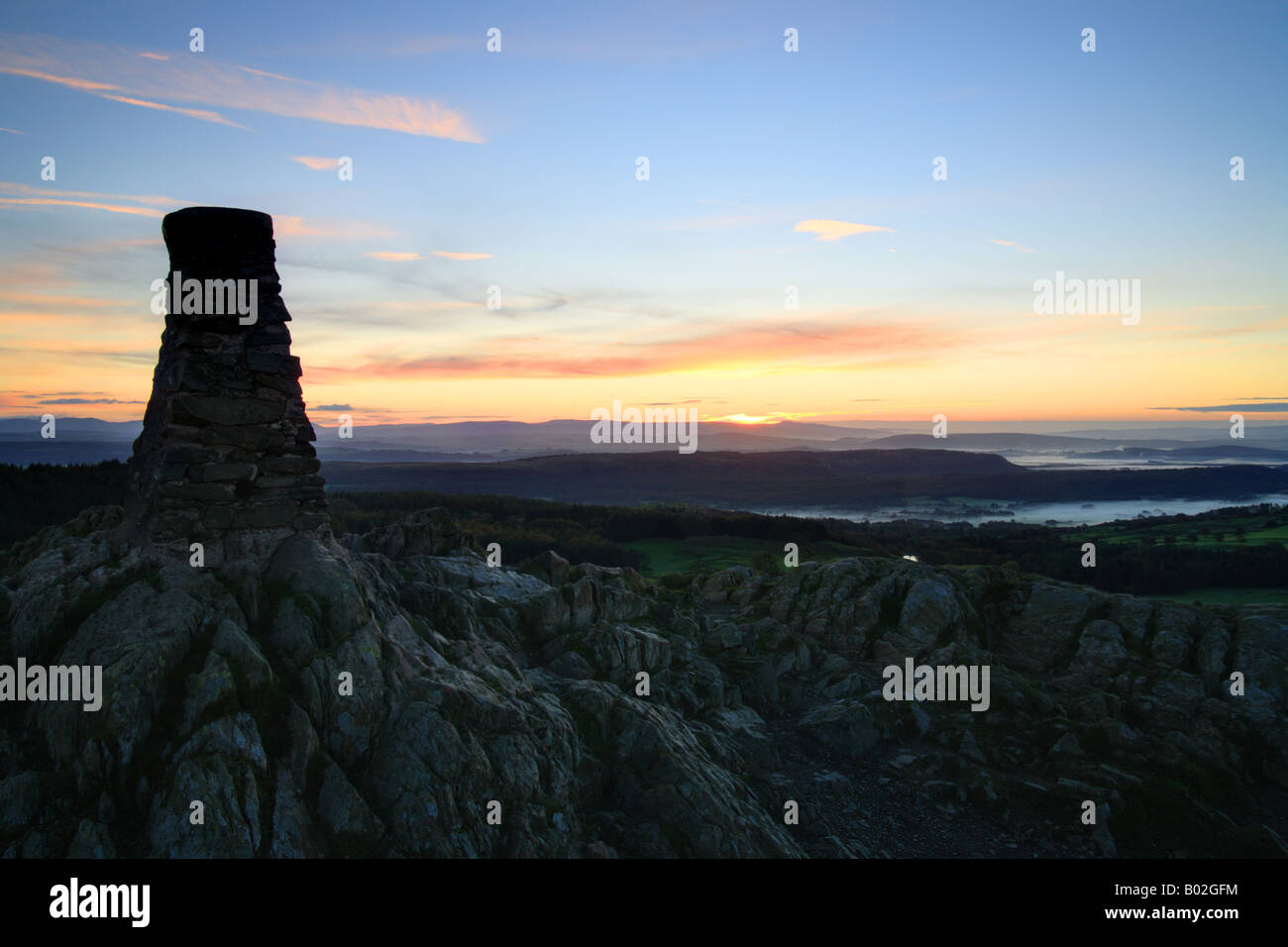 Cairn trig punto en la parte superior de 'cómo' Gummers al amanecer, Lake District, Cumbria, Inglaterra. Foto de stock