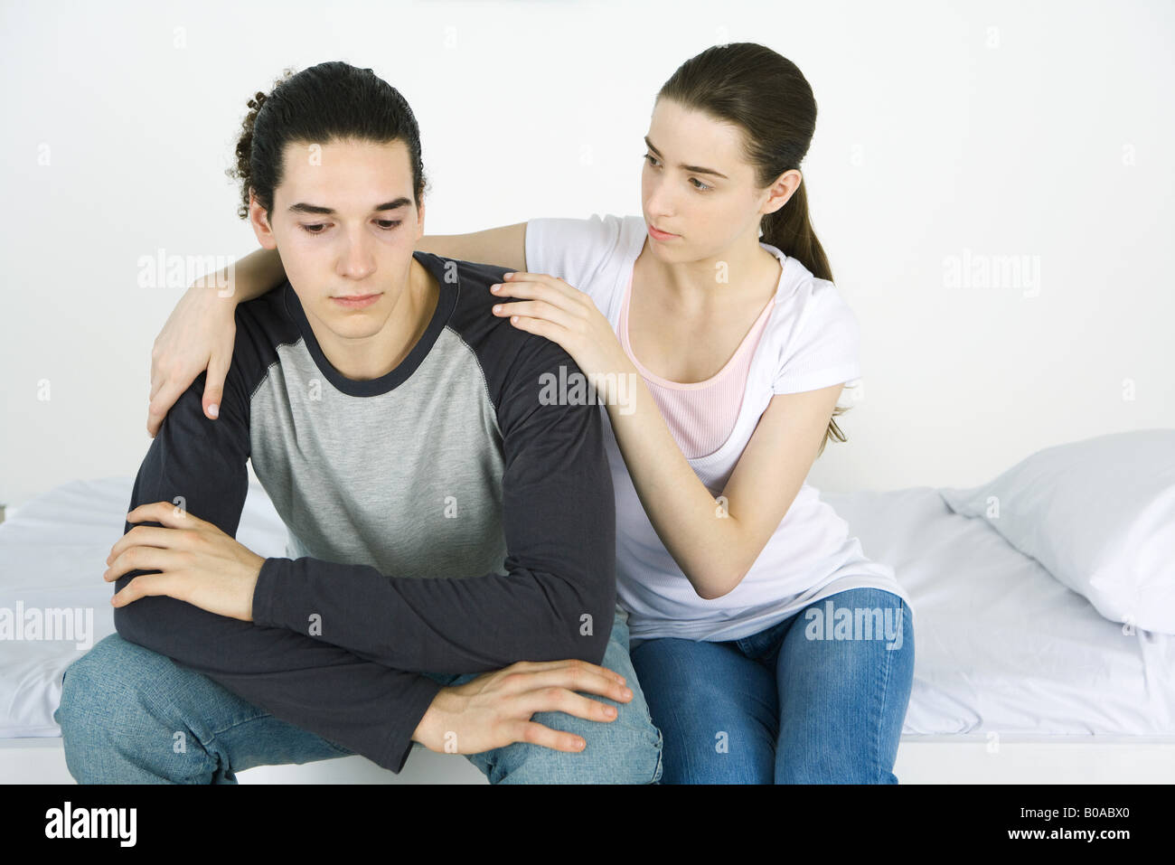 Pareja joven juntos en la cama, sexo femenino el brazo alrededor del hombro del macho Foto de stock
