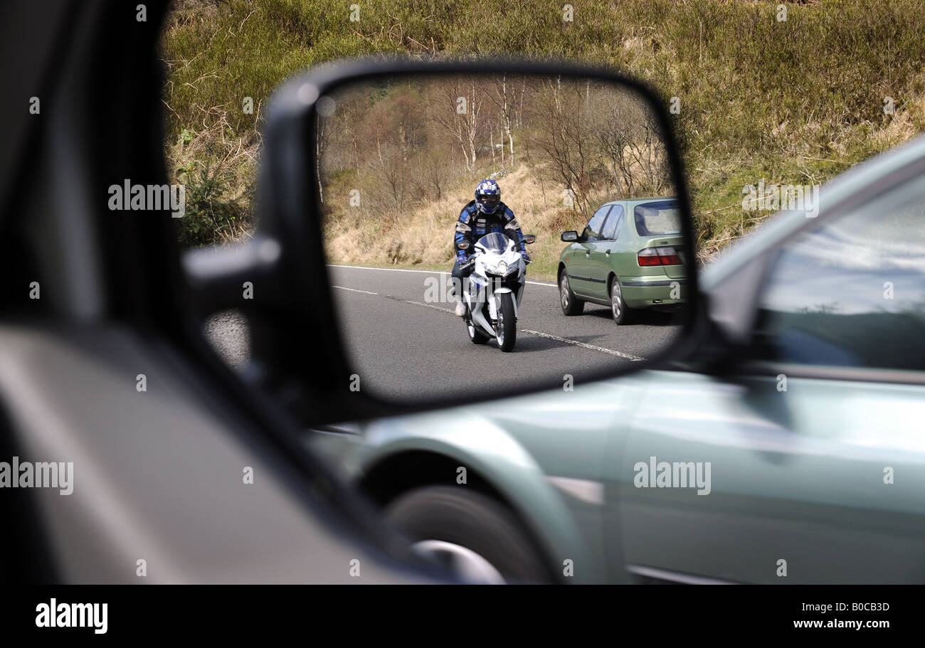 Un motociclista británica adelantamientos vistos en un espejo de ala de coche RE ciclistas visibilidad de concienciación de seguridad vial accidentes motos UK Foto de stock