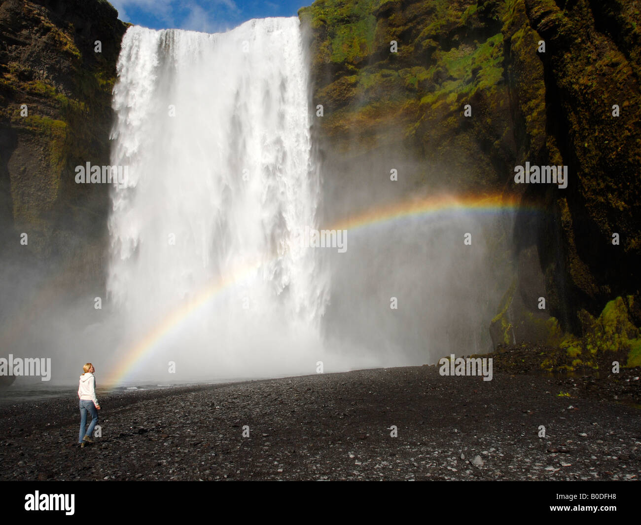 Una cascada, con un joven, en busca de una olla de oro al final del arco iris Foto de stock