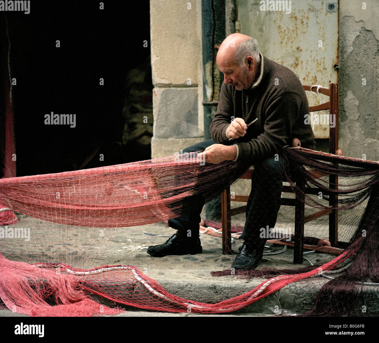 Antiguos pescadores reparando sus redes Cefalù Sicilia Italia UE. Foto de stock