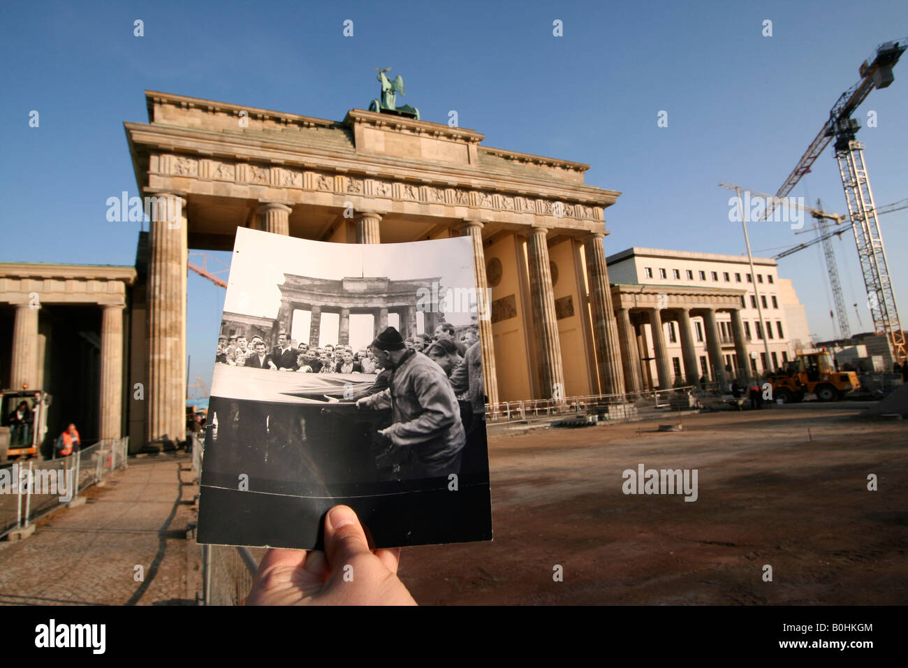 Entonces, como ahora, la mano sosteniendo una vieja foto en blanco y negro de una demostración del trabajador en el Brandenburger Tor o Puerta de Brandeburgo, B Foto de stock