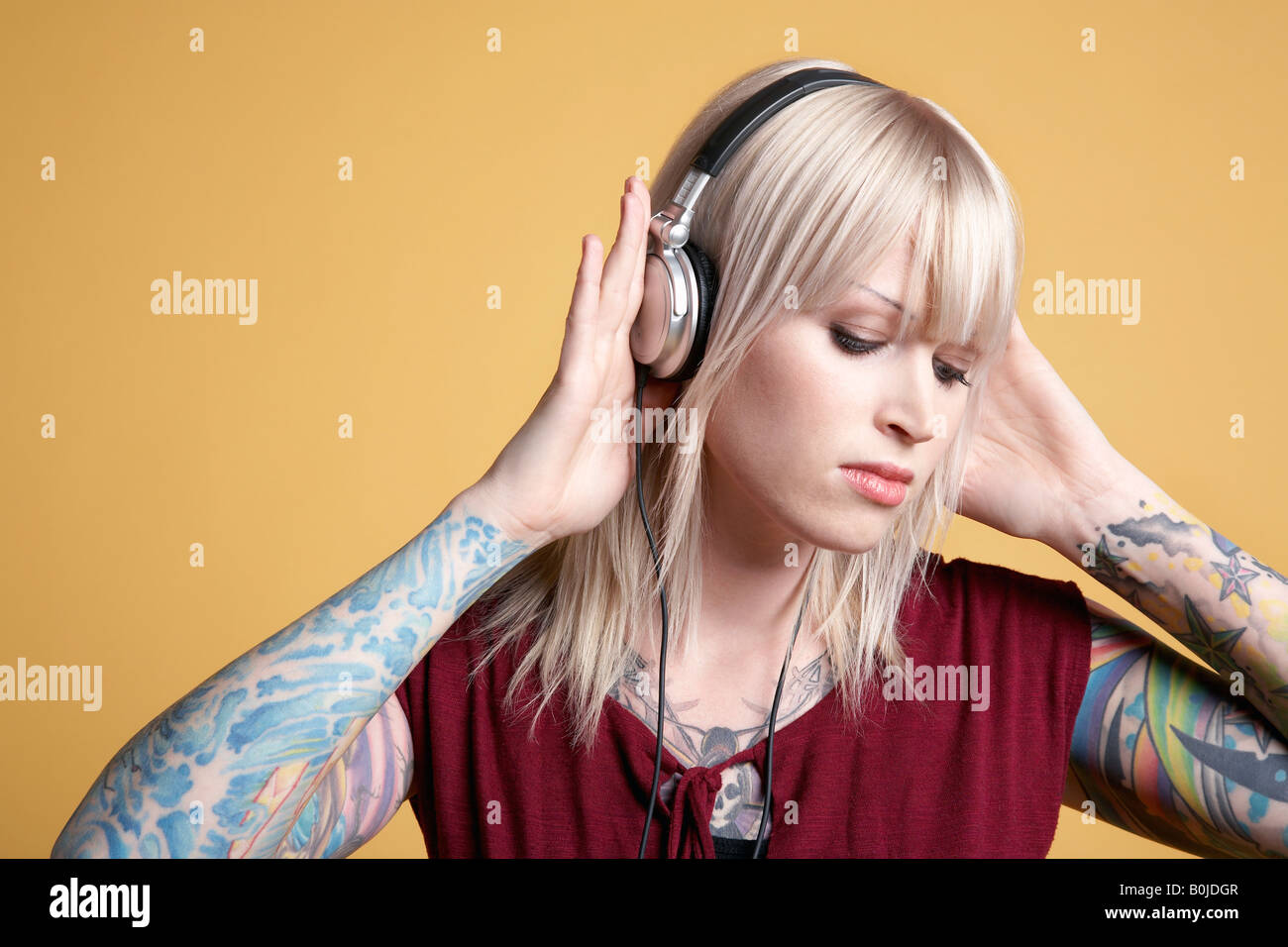 Joven mujer tatuada escuchando música en auriculares Fotografía de stock -  Alamy