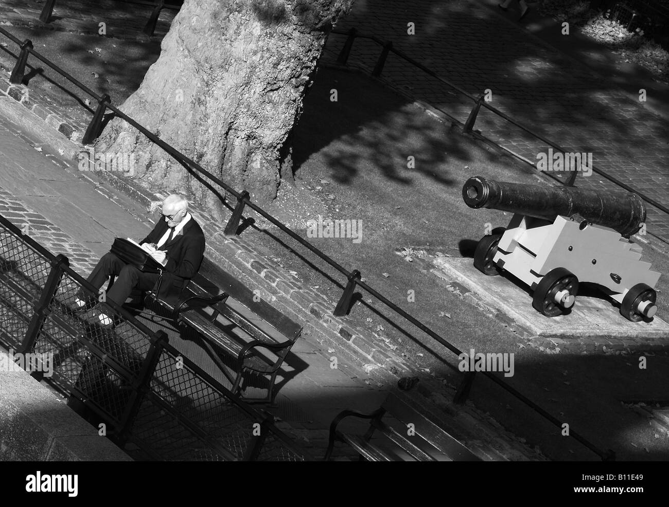 Un anciano sentado por sí mismo delante de un canon la fotografía de la calle fuera de la estación de metro de Tower Hill, en el centro de Londres. Foto de stock