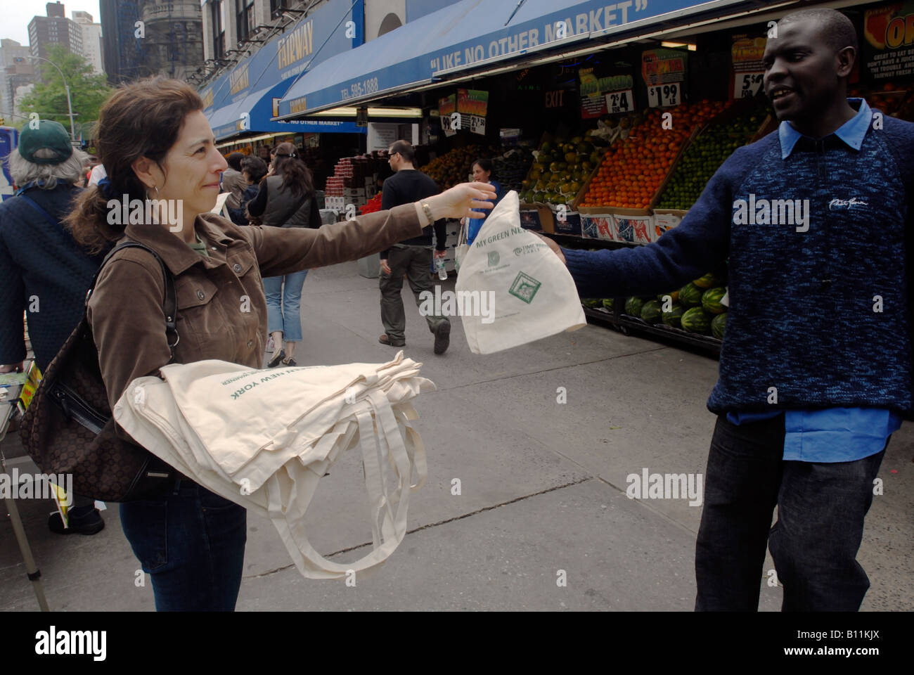 Voluntarios en frente de Fairway supermercado en Nueva York regalar bolsas de tela reutilizables para compradores para sustituir las bolsas de plástico Foto de stock