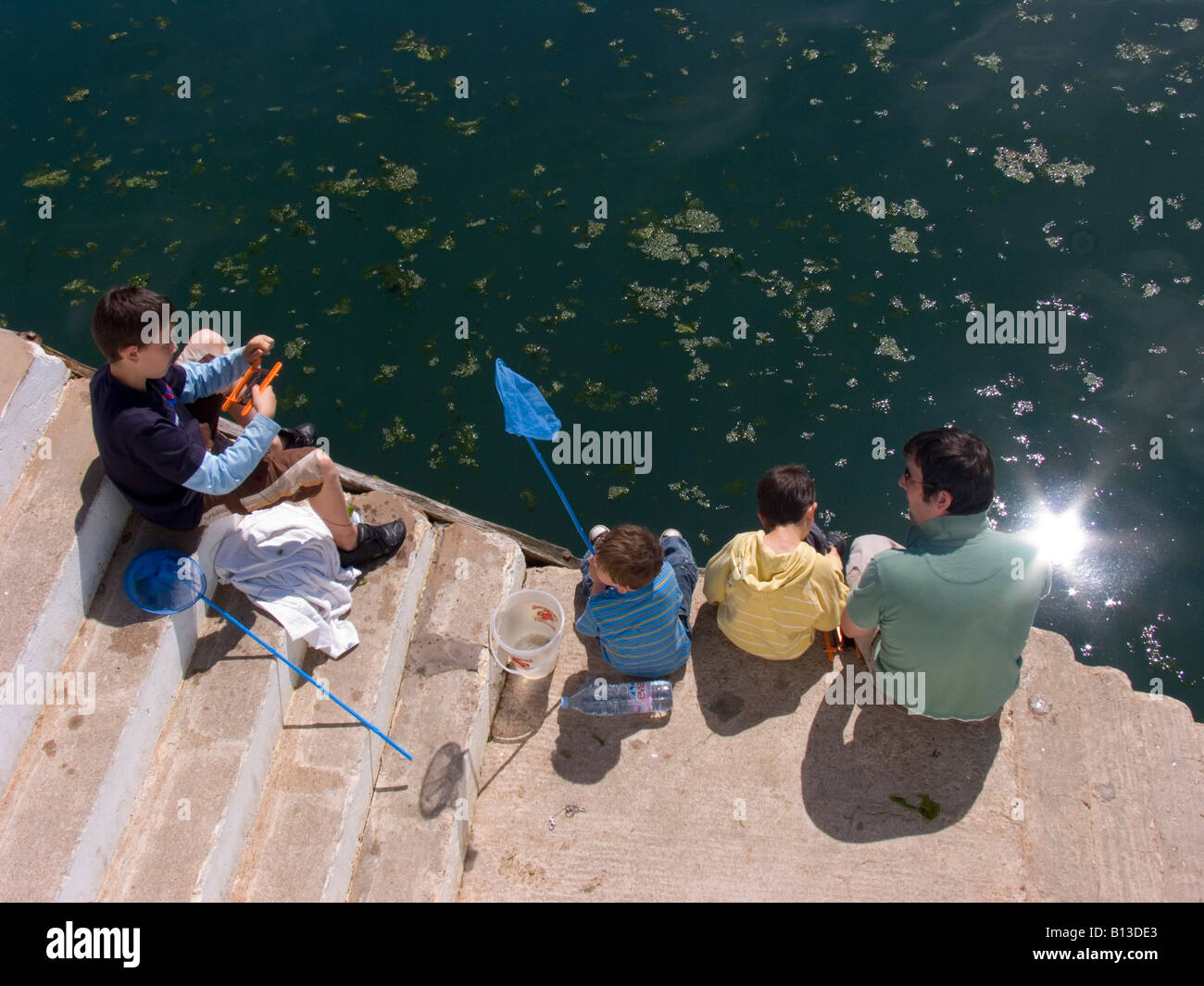 Vista aérea de un hombre y sus tres hijos sentados en los escalones del puerto y capturando los cangrejo con sus redes. Paignton. Devon. REINO UNIDO Foto de stock