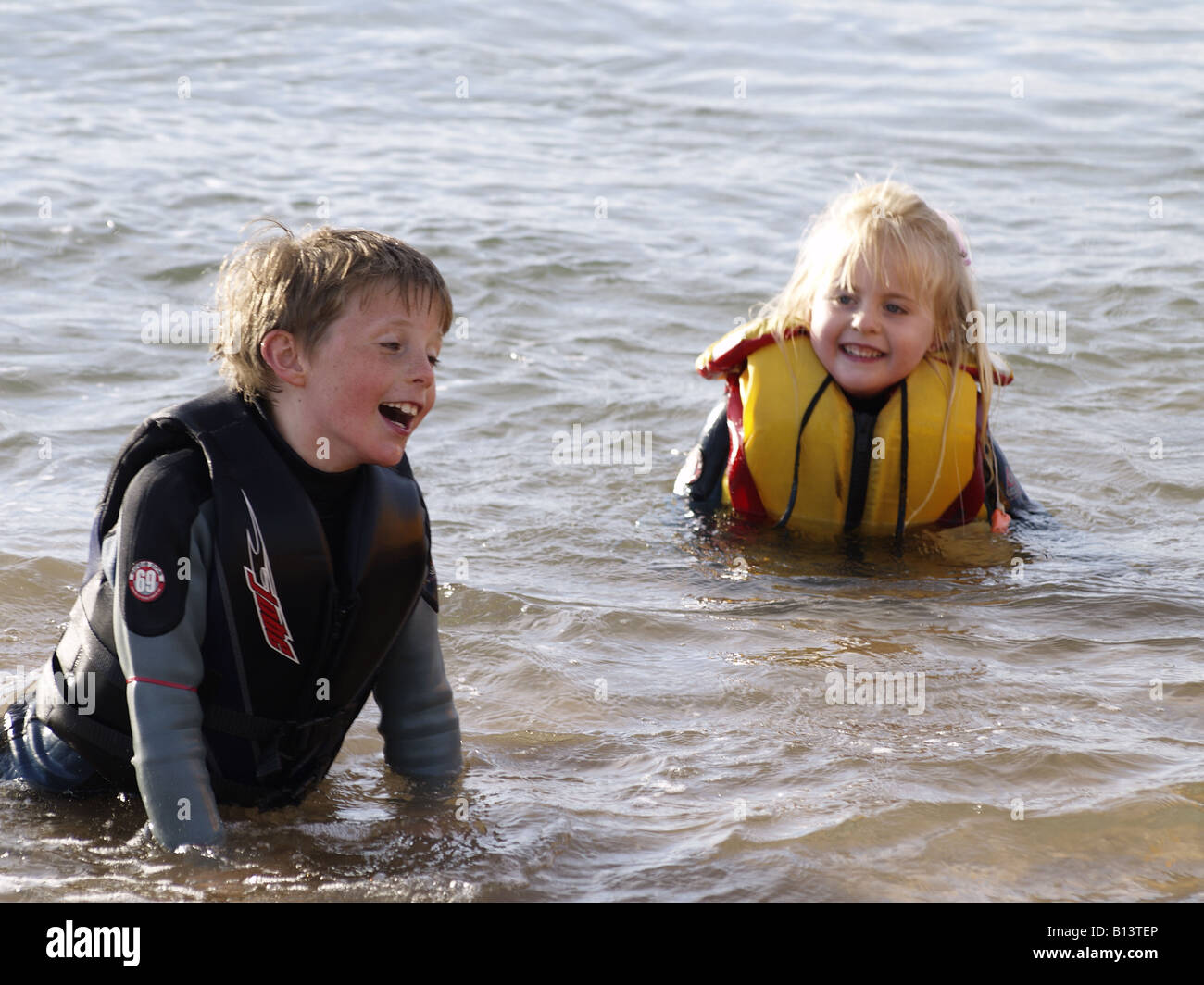 Emborracharse tramo acantilado Niño y niña, vestida con un traje de neopreno y ayudas a la flotación,  jugando en el mar Fotografía de stock - Alamy