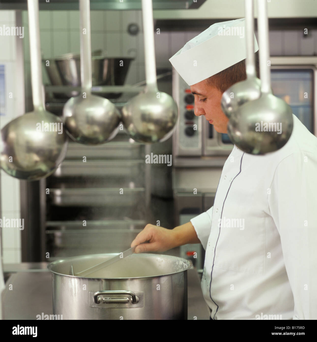 Cocine revolviendo en una olla, comedor cocina, cuchara en la parte delantera, Alemania Foto de stock