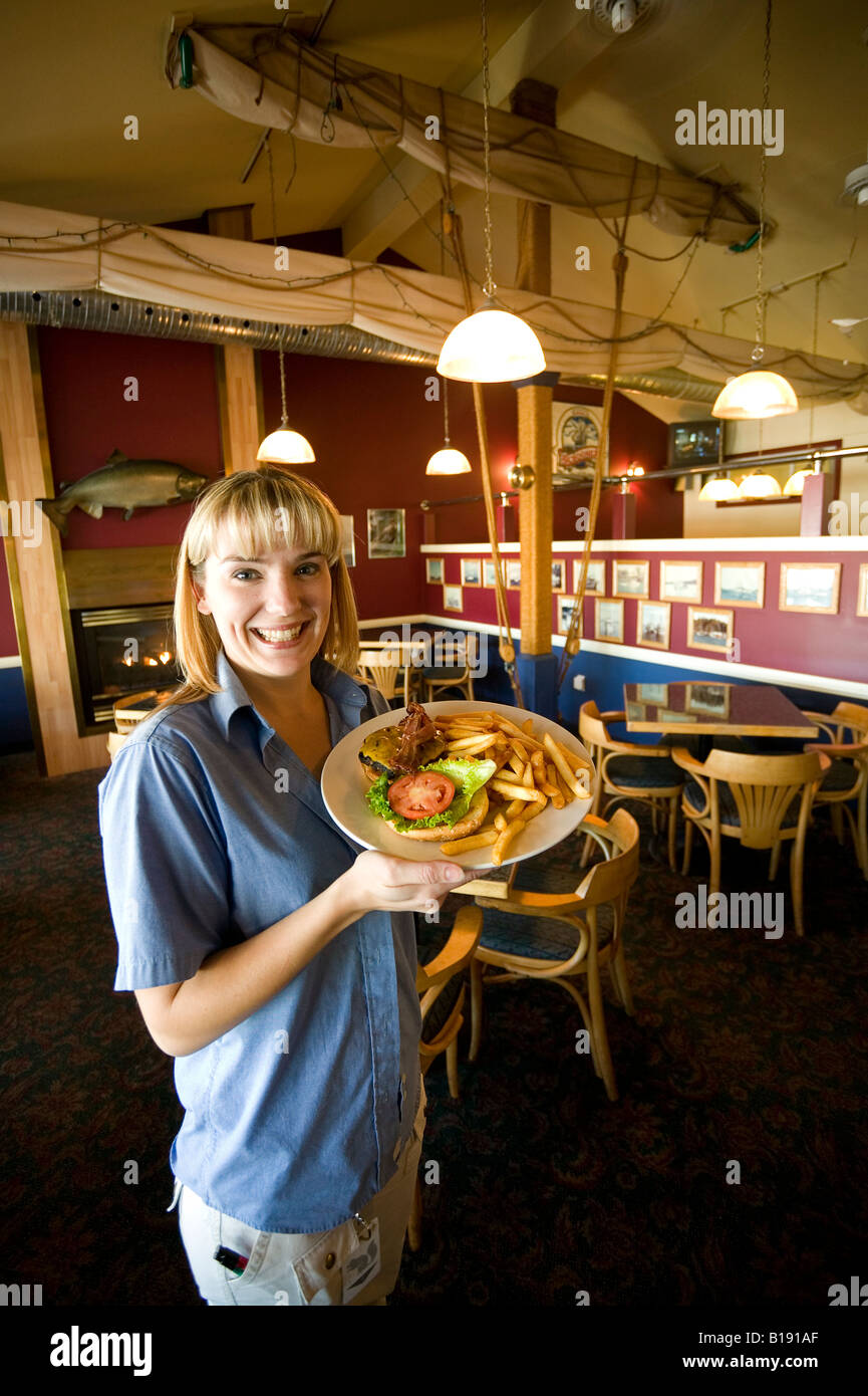 Servidor femenino en el Quarterdeck Bar con un plato de hamburguesas. Port Hardy, Isla de Vancouver, British Columbia, Canadá. Foto de stock