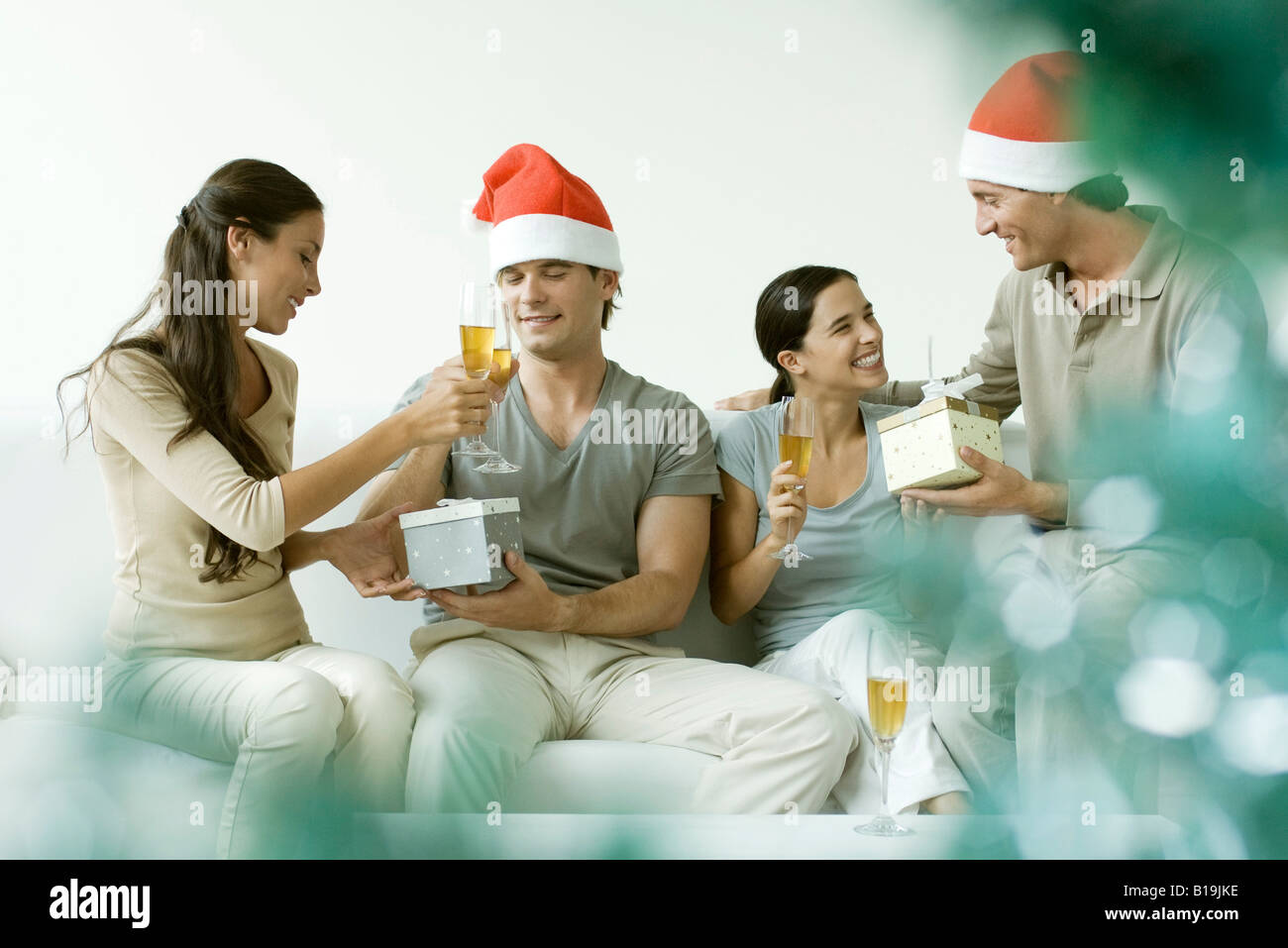 Dos parejas intercambio de regalos de Navidad, bebiendo champán, hombres  vestidos de gorro de Papá Noel Fotografía de stock - Alamy