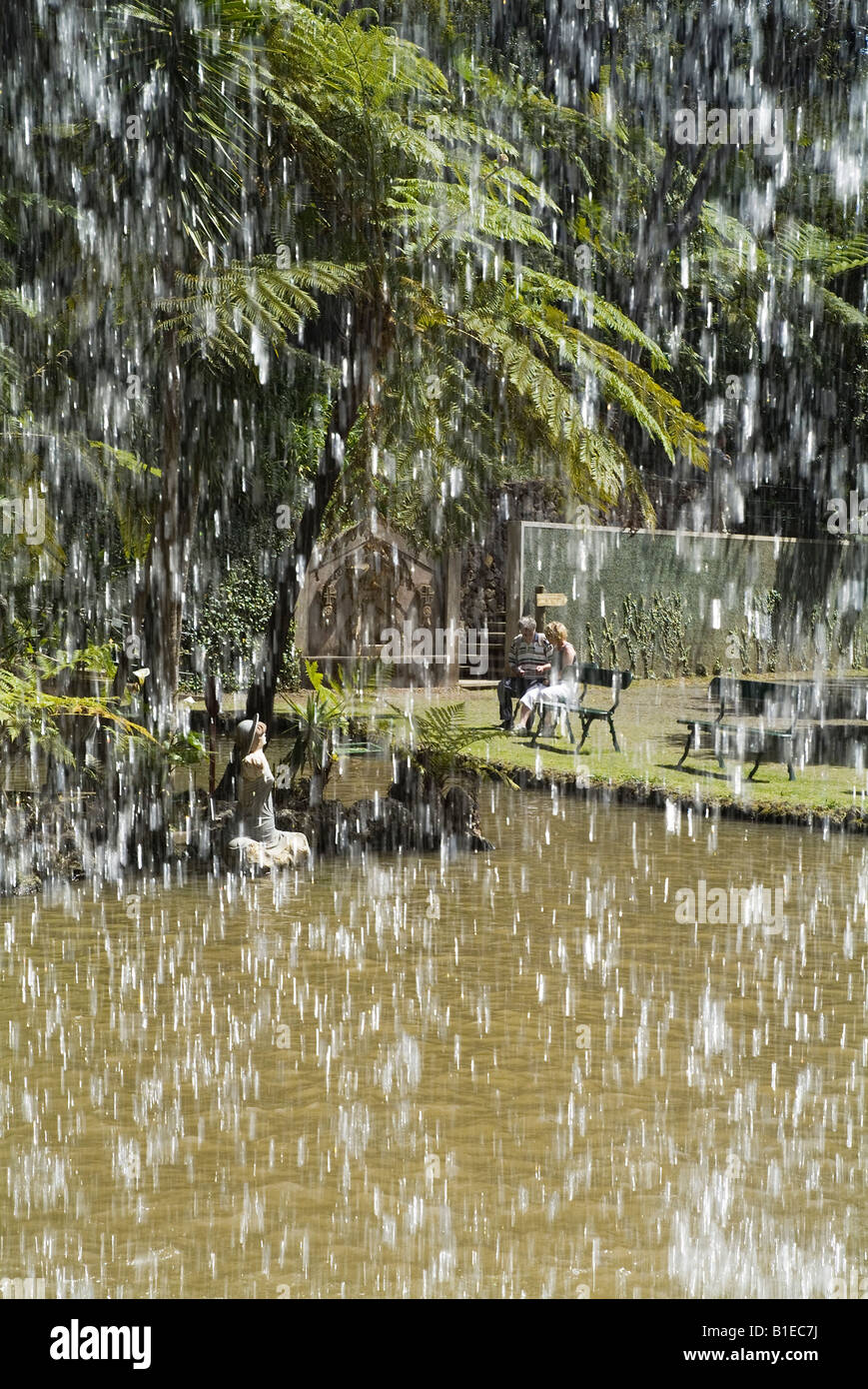 dh Monte Palace Tropical Garden MONTE MADEIRA Waterfall y los turistas en bancos relajantes jardines estanque Foto de stock