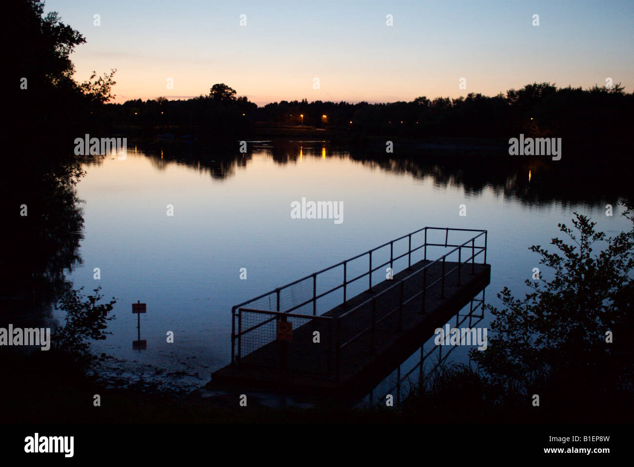 De Woking (Surrey, Inglaterra Goldsworth parque del lago al atardecer con un embarcadero en primer plano Foto de stock