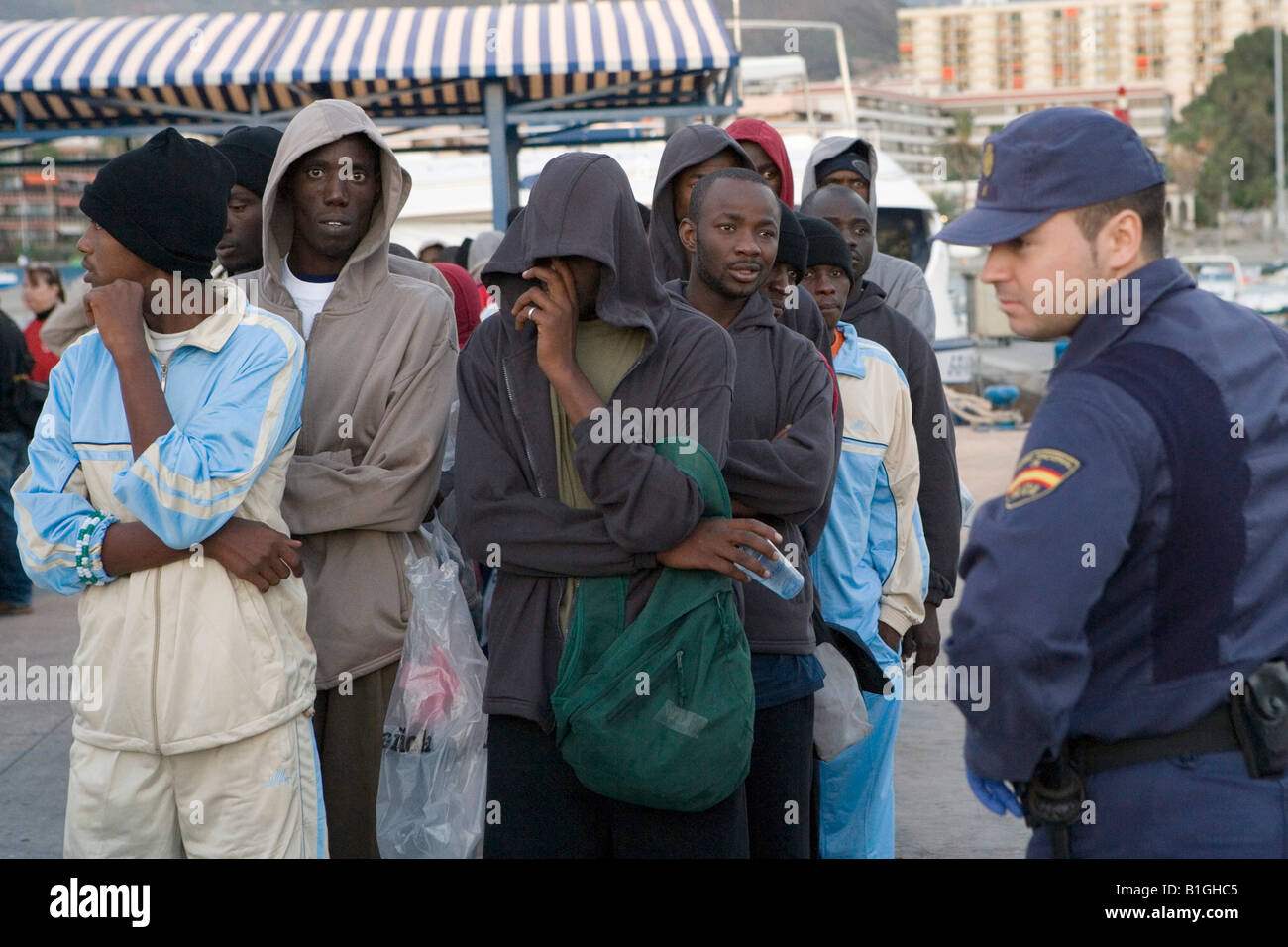 Los refugiados africanos y un hombre de la policía española Foto de stock