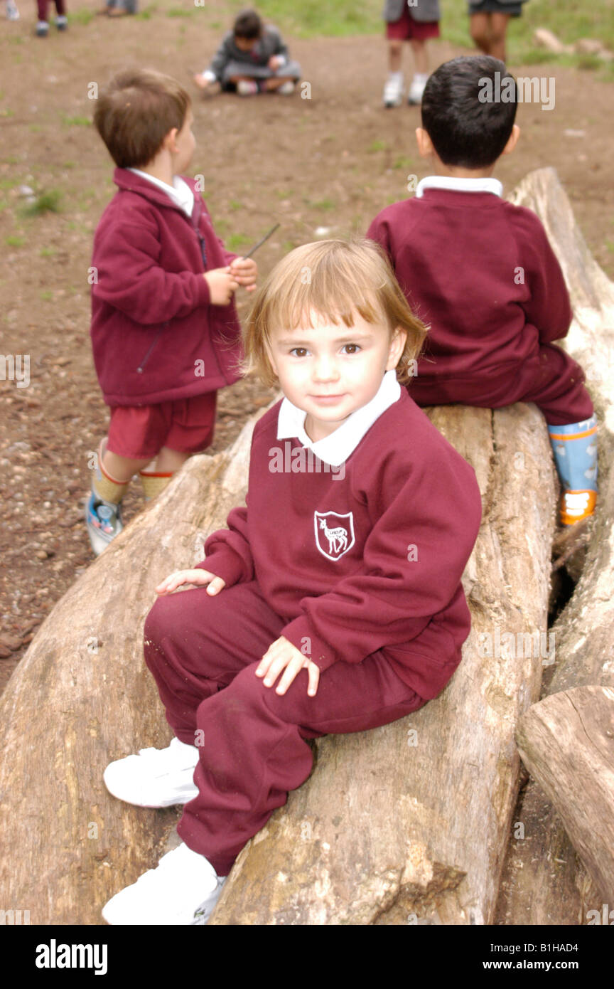 Las niñas un muchachos sentados sobre troncos en el parque en uniforme escolar Foto de stock