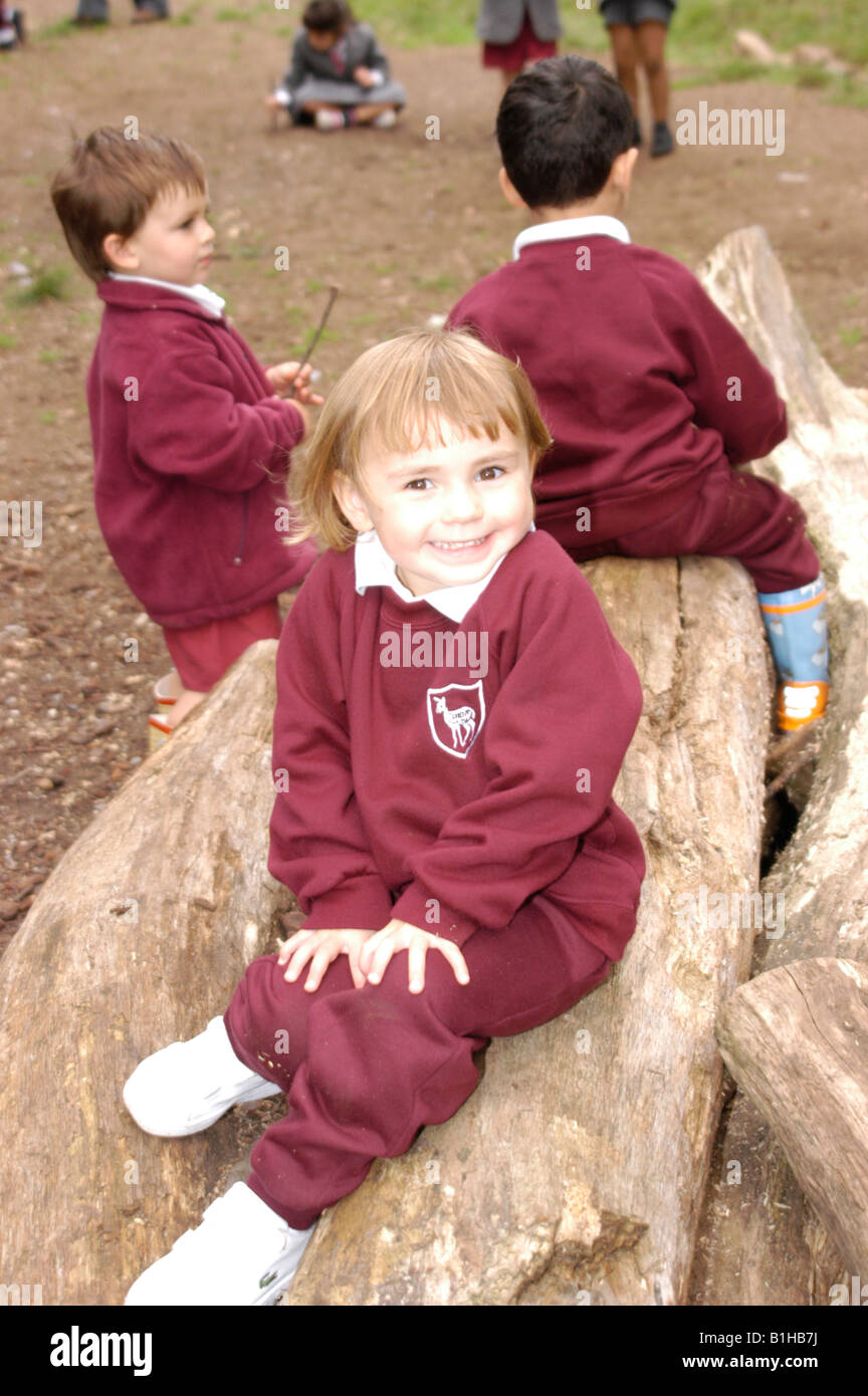 Niños sentados sobre troncos en estacionamiento en uniforme escolar Foto de stock