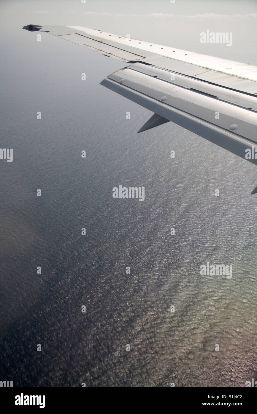 Alto nivel vista aérea oblicua de alas de avión volando sobre el mar Foto de stock