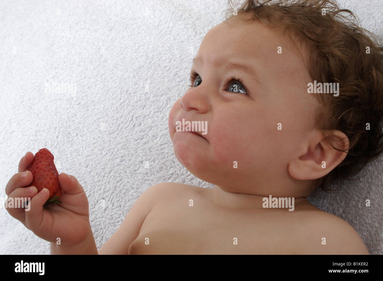 Little Baby comer fresas les disgusta el sabor de los alimentos sólidos Foto de stock