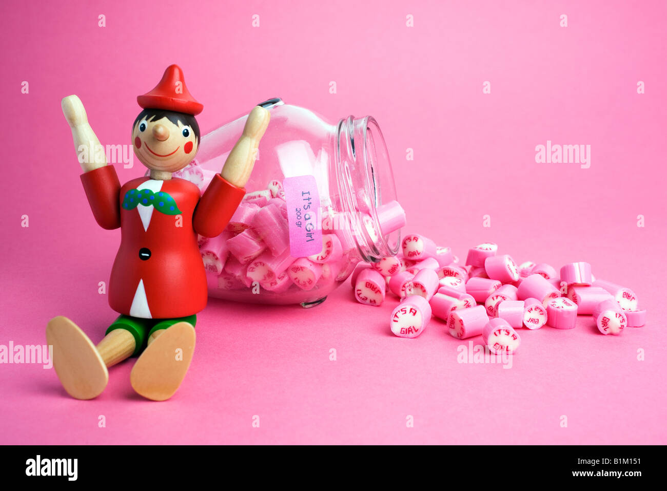 Pinocho de madera juguete chico sentado junto a un frasco de "es una niña'  rock dulces Fotografía de stock - Alamy