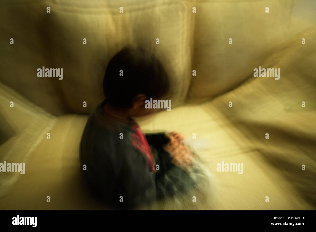 La larga exposición deliberada con el movimiento de la cámara y del sujeto creando imagen abstracta Boy uno de seis años se sienta en el sofá Foto de stock