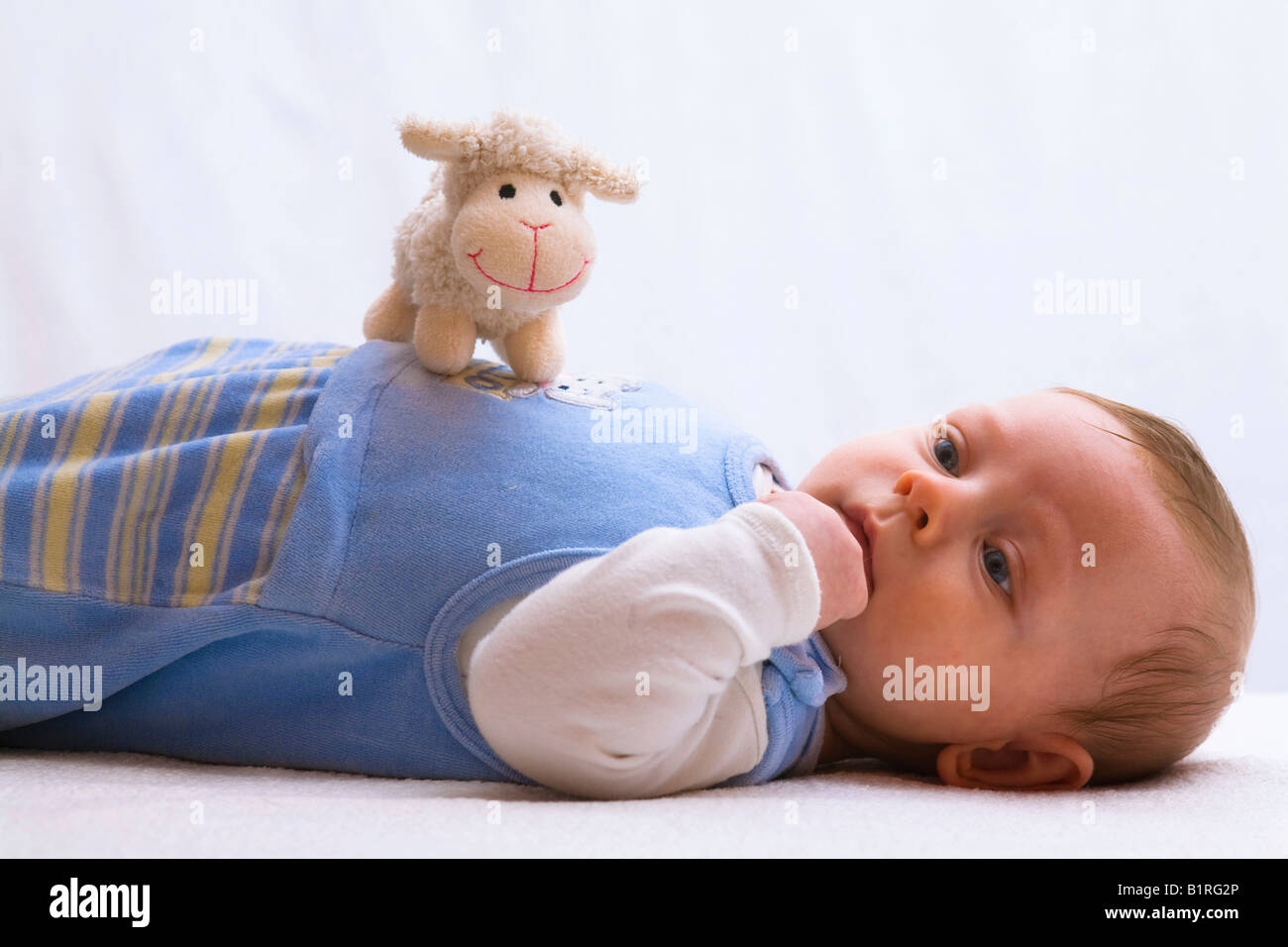Bebé de 3 meses alcanzar para un animal de juguete Foto de stock
