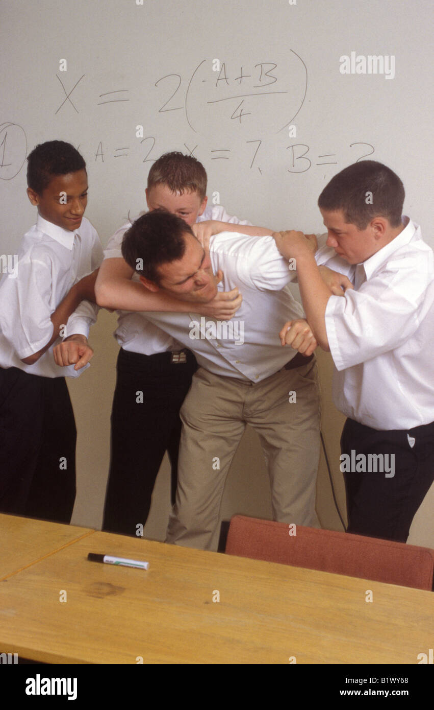 Pandilla de chicos atacando a un profesor en el aula Foto de stock