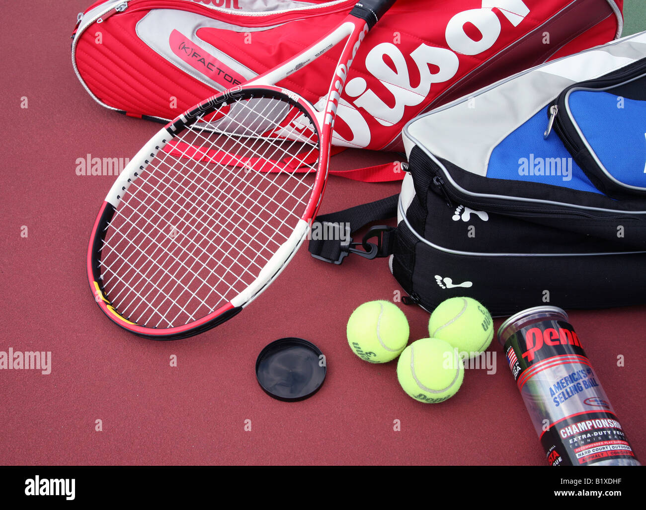 Dos bolsas de raqueta de tenis con dos raquetas de tenis sentar cruzado en  la parte superior y un contenedor de pelotas de tenis acostado sobre una  pista de tenis Fotografía de