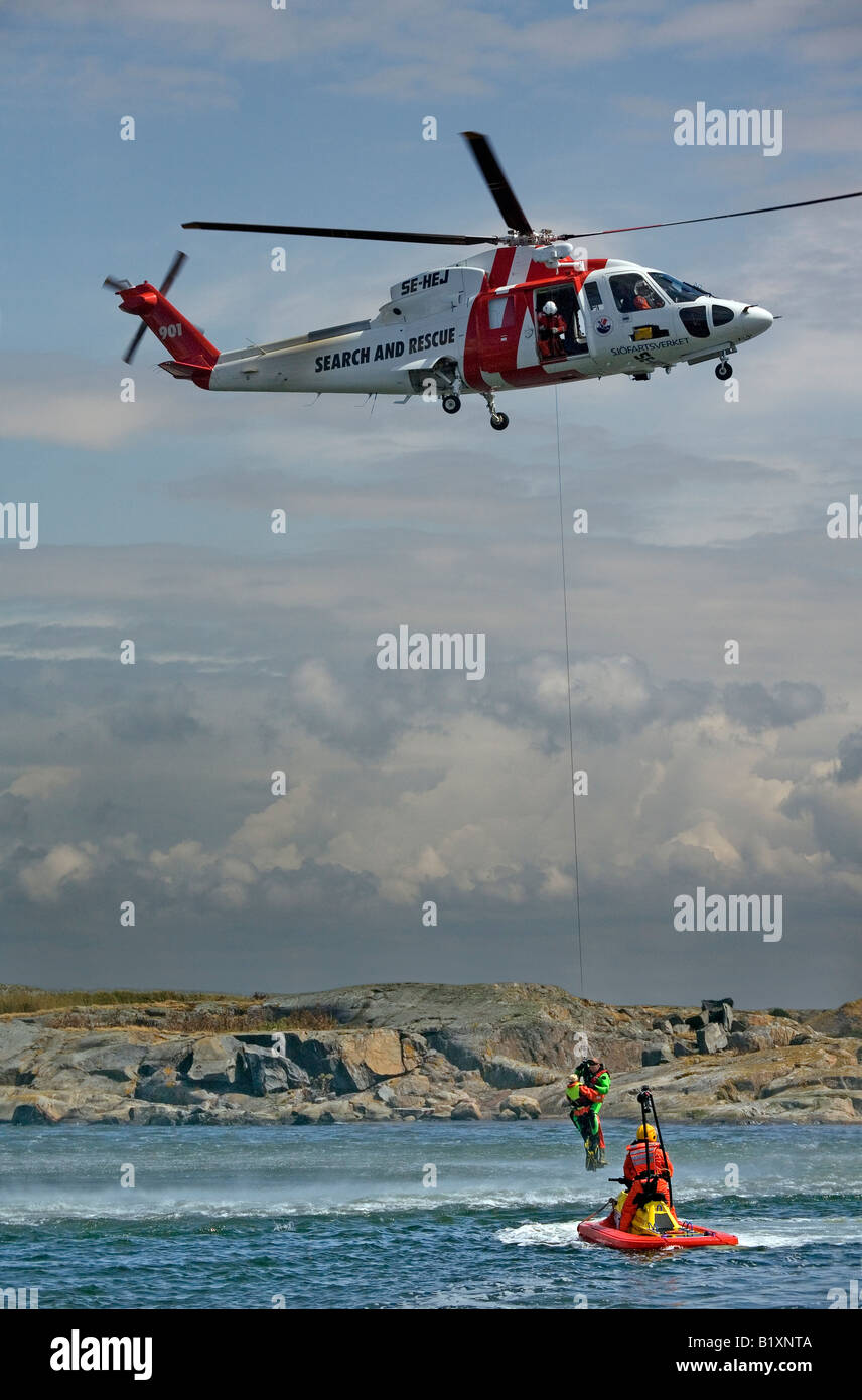 Búsqueda y Rescate en helicóptero SAR polipastos equipo una persona por ayuda de nadador de rescate Foto de stock