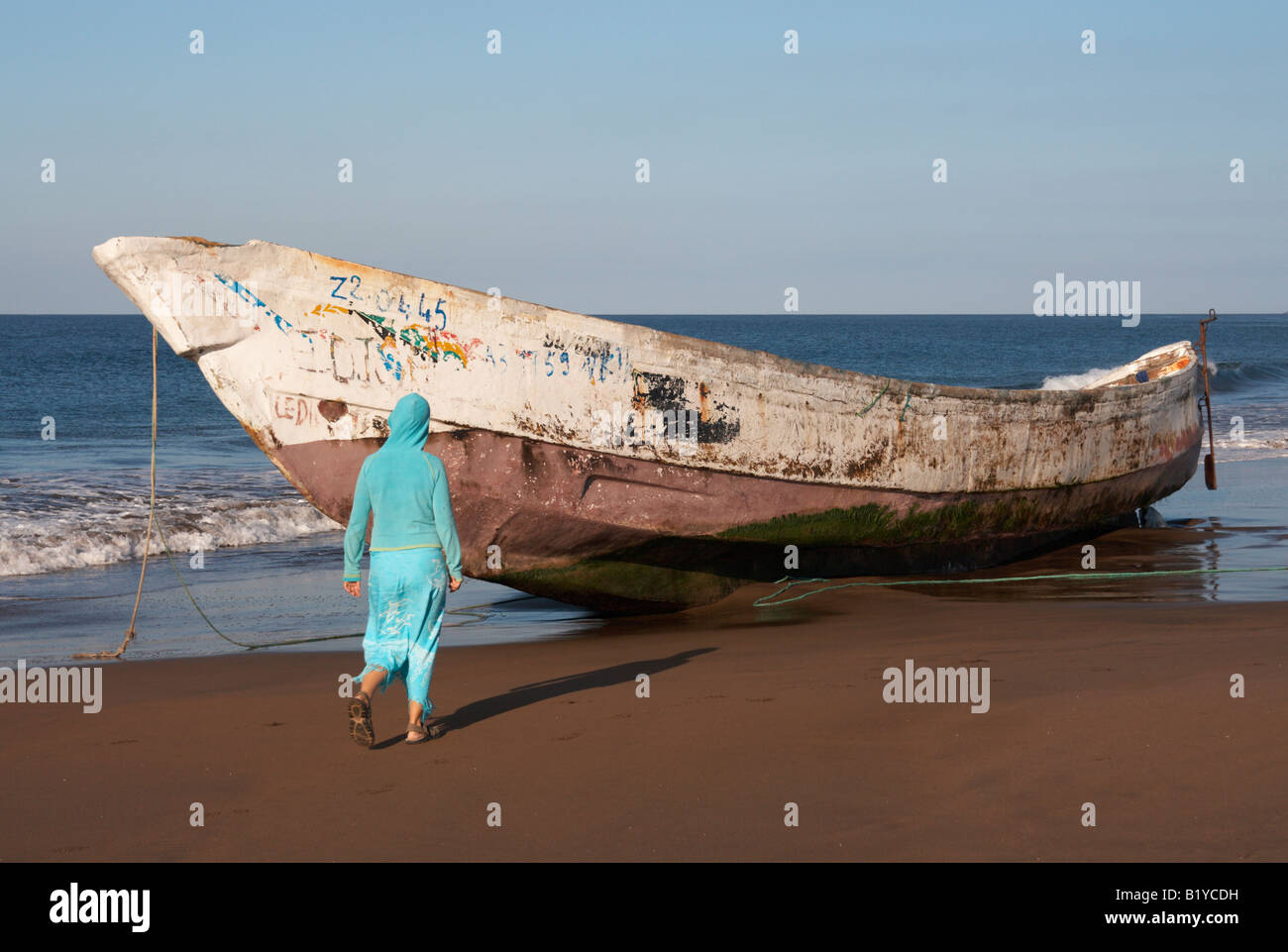 Mujer local cerca de barco que dos horas antes había aterrizado en esta playa en Tenerife con 150 inmigrantes ilegales procedentes de África. Foto de stock