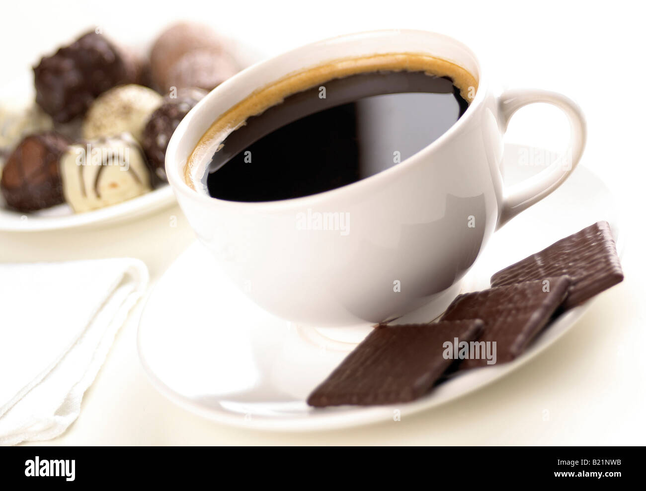 Taza blanca con café negro y tres después de la cena, chocolate con menta  con más chocolates en el fondo fuera de foco Fotografía de stock - Alamy